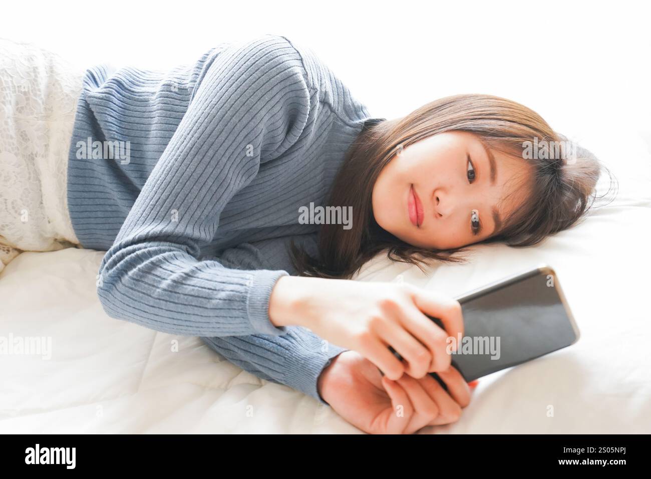 Jeune femme utilisant le téléphone avant d'aller au lit dans le lit Banque D'Images Jeune femme utilisant le téléphone avant d'aller au lit dans le lit Banque D'Images