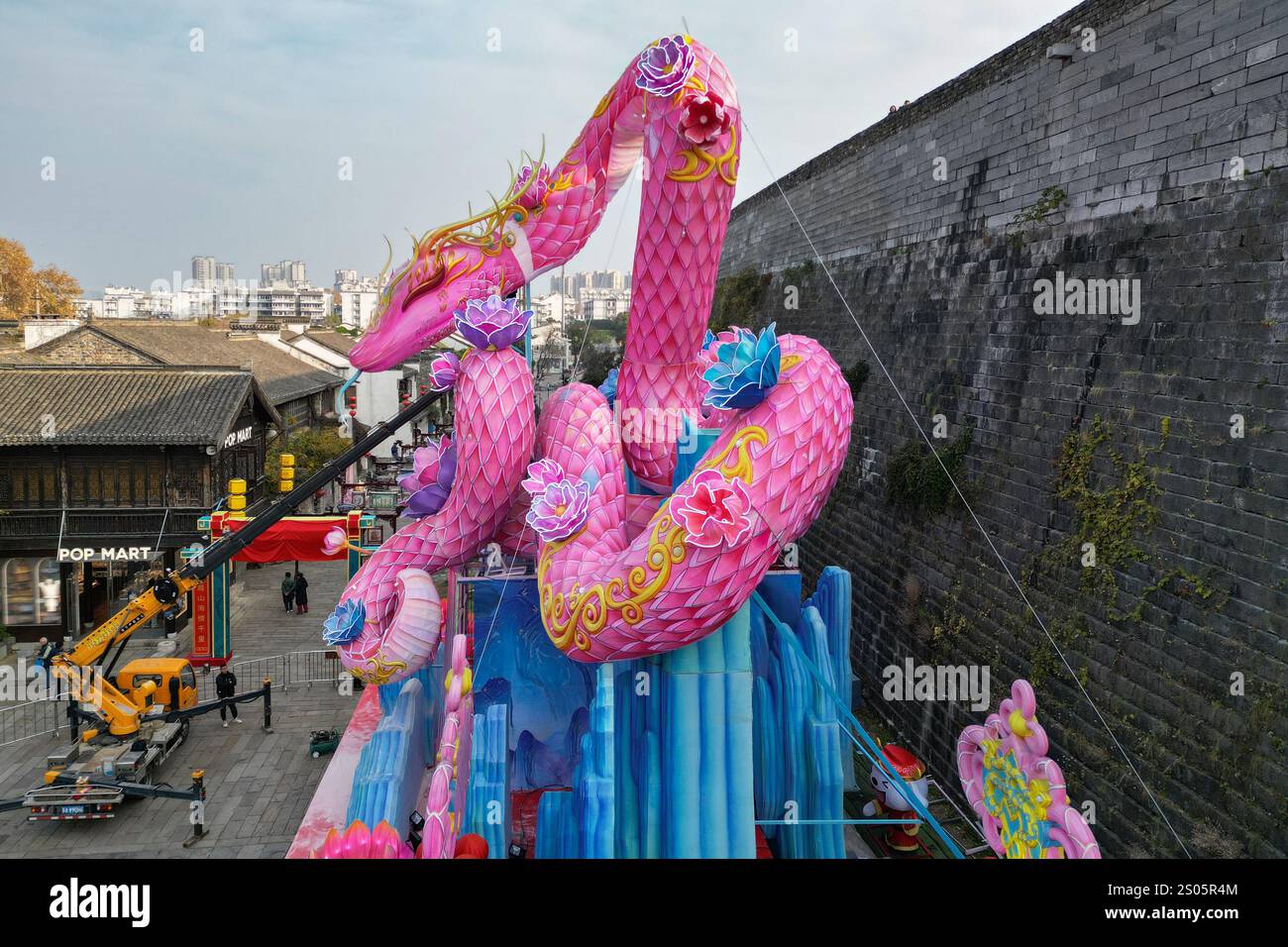Nanjing, Chine.24 décembre 2024. Les ouvriers ont installé une lanterne géante en forme de serpent sous le mur de la ville de Ming pour accueillir le nouvel an chinois 2025, l'année du serpent, le 24 décembre 2024 à Nanjing, dans la province chinoise du Jiangsu. Crédit : Yang Bo/China News Service/Alamy Live News Banque D'Images