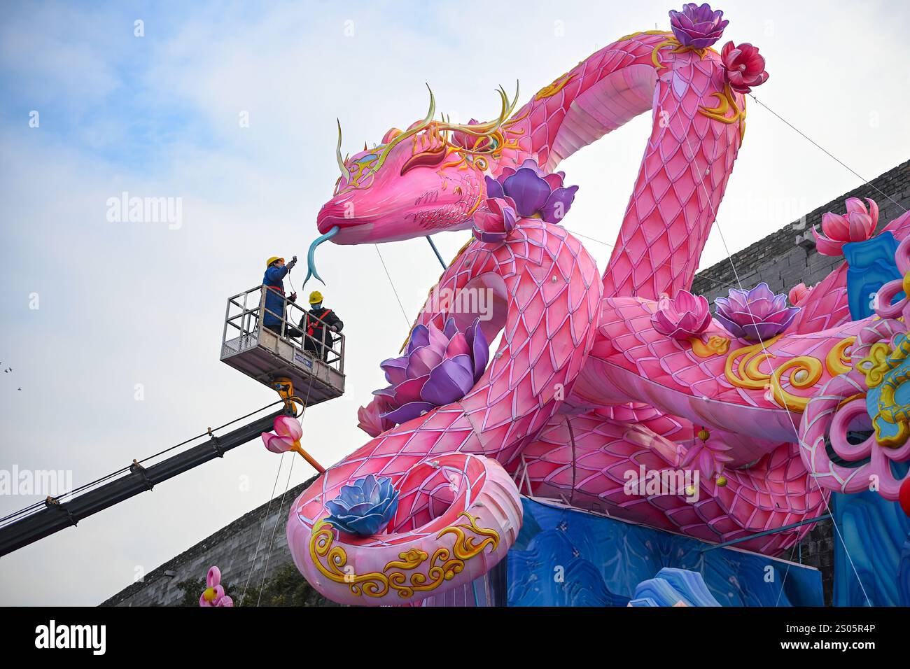 Nanjing, Chine.24 décembre 2024. Les ouvriers ont installé une lanterne géante en forme de serpent sous le mur de la ville de Ming pour accueillir le nouvel an chinois 2025, l'année du serpent, le 24 décembre 2024 à Nanjing, dans la province chinoise du Jiangsu. Crédit : Yang Bo/China News Service/Alamy Live News Banque D'Images