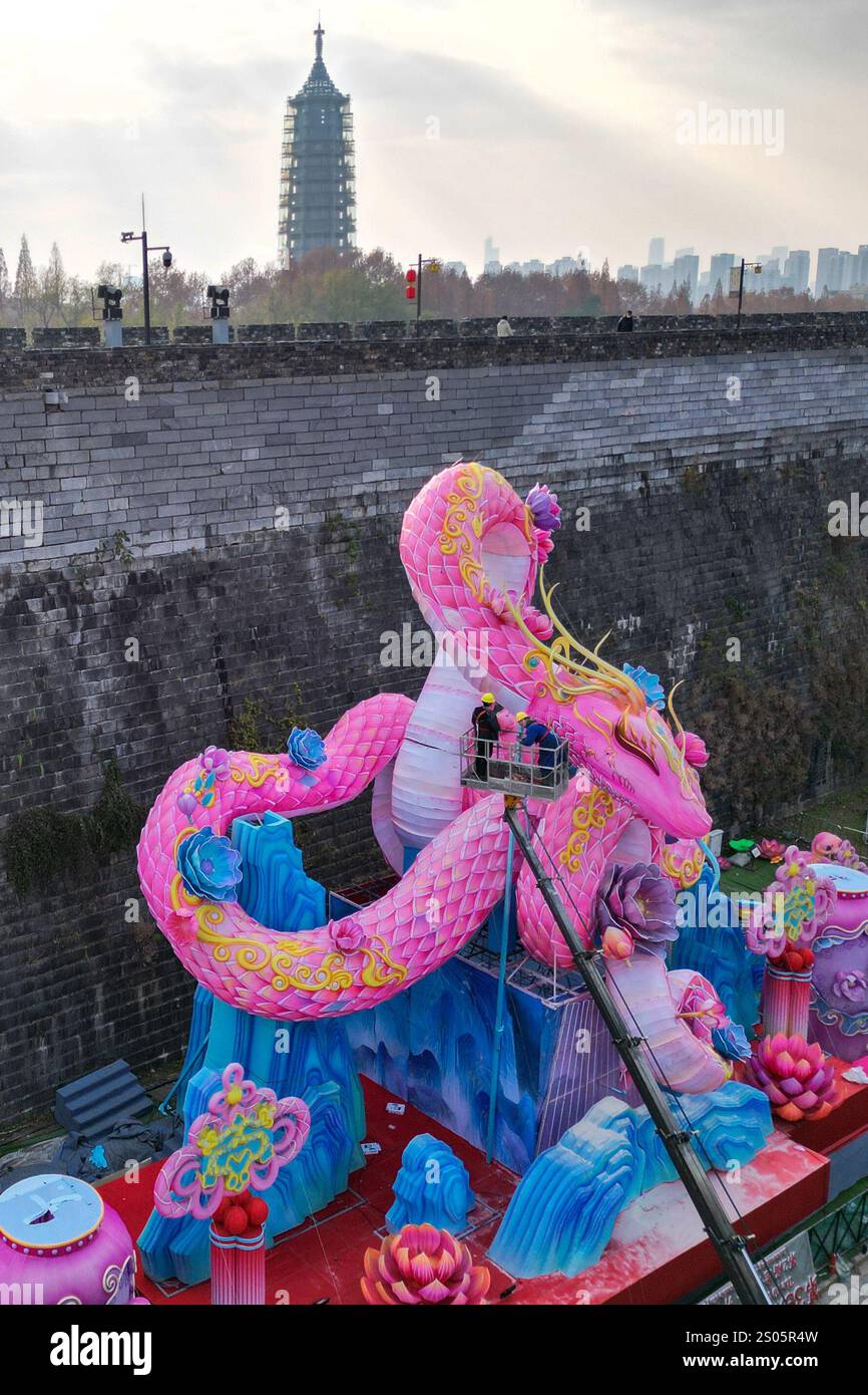Nanjing, Chine.24 décembre 2024. Les ouvriers ont installé une lanterne géante en forme de serpent sous le mur de la ville de Ming pour accueillir le nouvel an chinois 2025, l'année du serpent, le 24 décembre 2024 à Nanjing, dans la province chinoise du Jiangsu. Crédit : Yang Bo/China News Service/Alamy Live News Banque D'Images