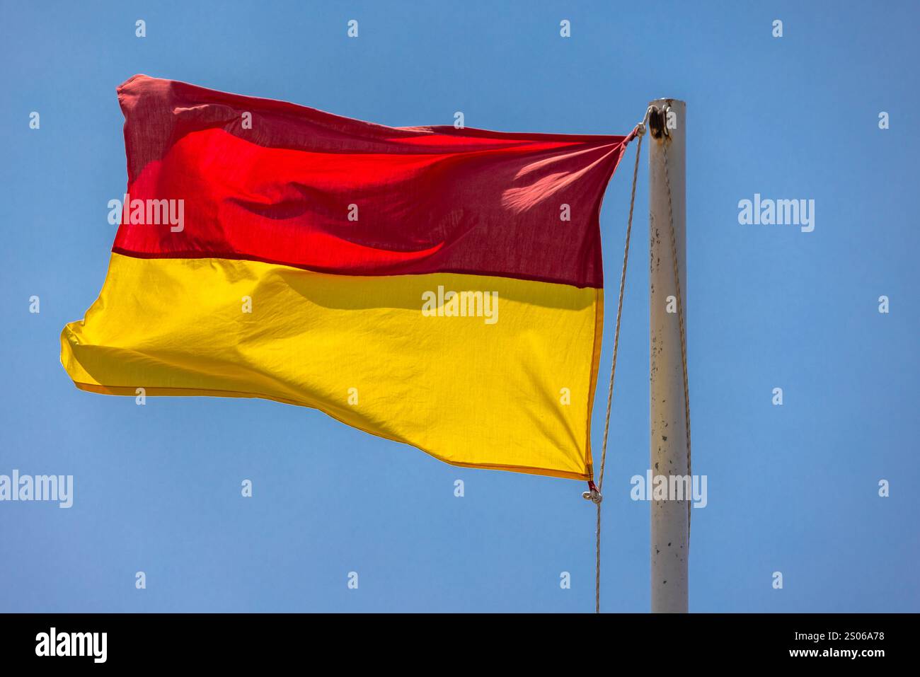 Drapeau de plage d'avertissement rouge et jaune est sous le ciel bleu sur une journée ensoleillée, équipement de sécurité de plage Banque D'Images Drapeau de plage d'avertissement rouge et jaune est sous le ciel bleu sur une journée ensoleillée, équipement de sécurité de plage Banque D'Images