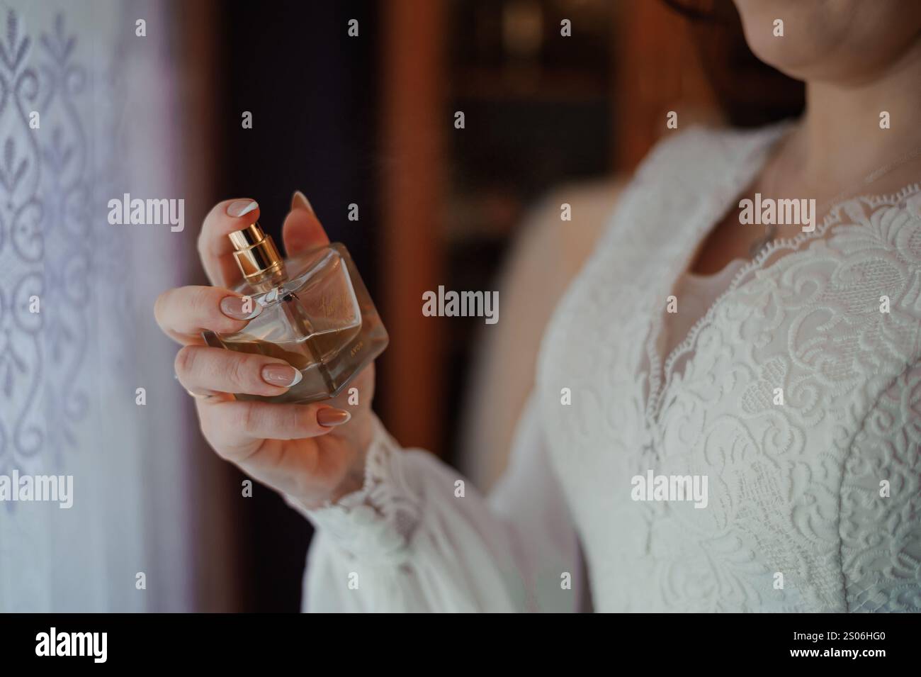 Femme élégante tenant une bouteille de parfum Vintage en lumière douce. Banque D'Images