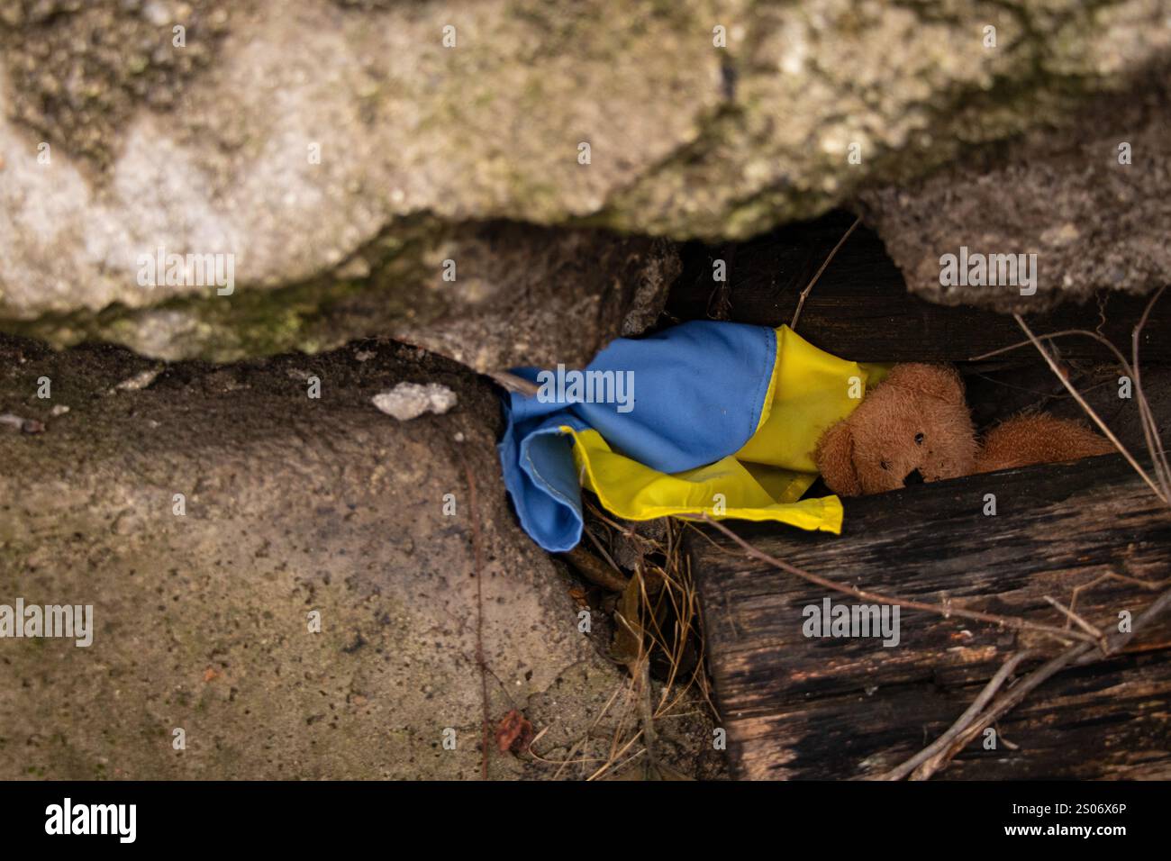 Ours en peluche brun pour enfants et drapeau ukrainien sous des décombres en Ukraine, guerre Banque D'Images