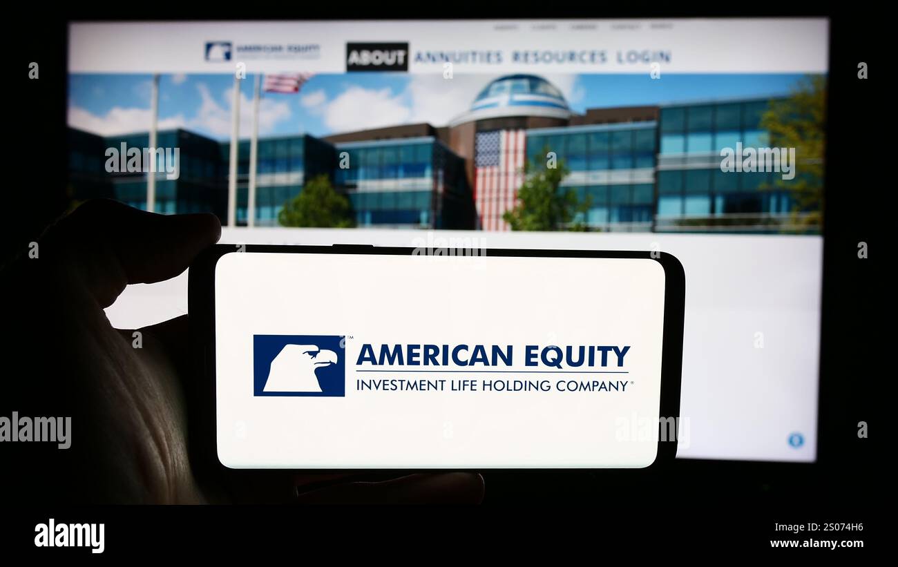Dans cette illustration de photo, une personne tient un téléphone portable avec le logo de American Equity Investment Life Holding Company devant la page Web de l'entreprise. Banque D'Images