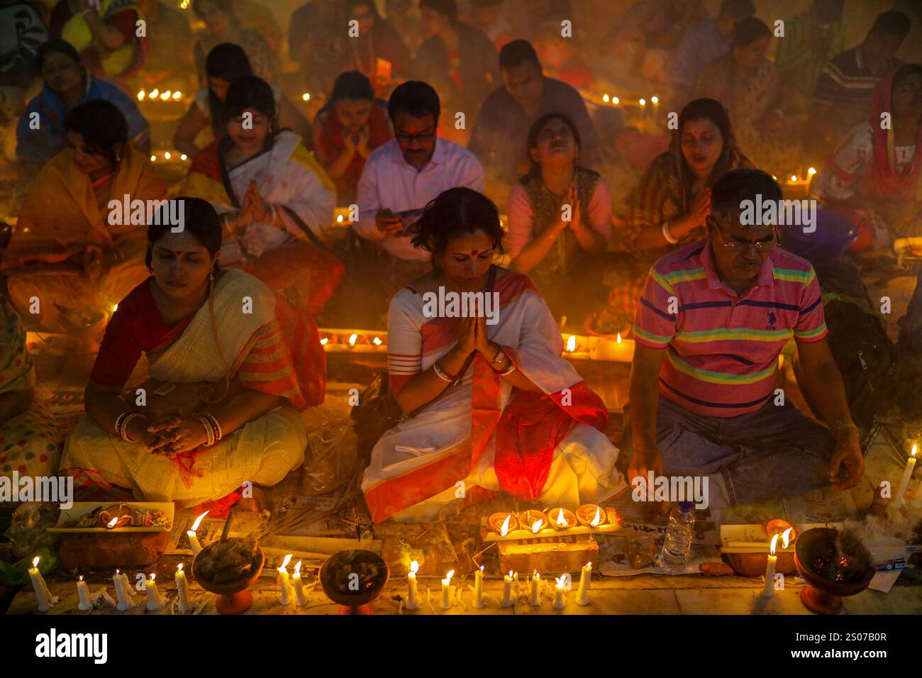 Les dévots s'assoient dans la prière avec de l'encens brûlants et des lampes à huile brillantes pendant Rakher Upobash, un festival de jeûne sacré, à l'Ashram i de Lokenath Brahmachari Banque D'Images