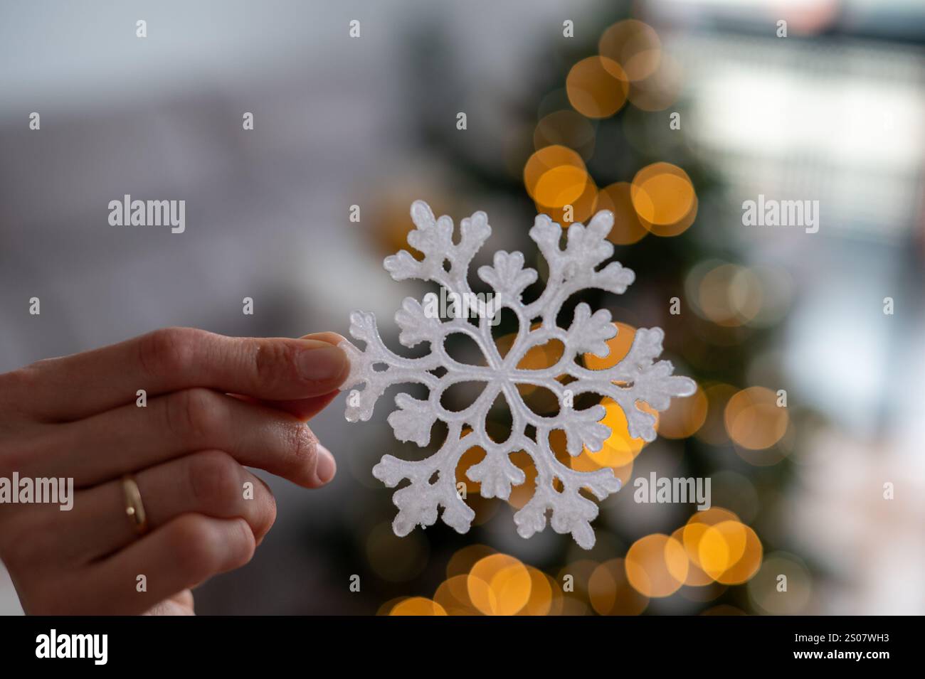 Une personne tient un flocon de neige dans sa main. Le flocon de neige est blanc et a un design unique. Banque D'Images