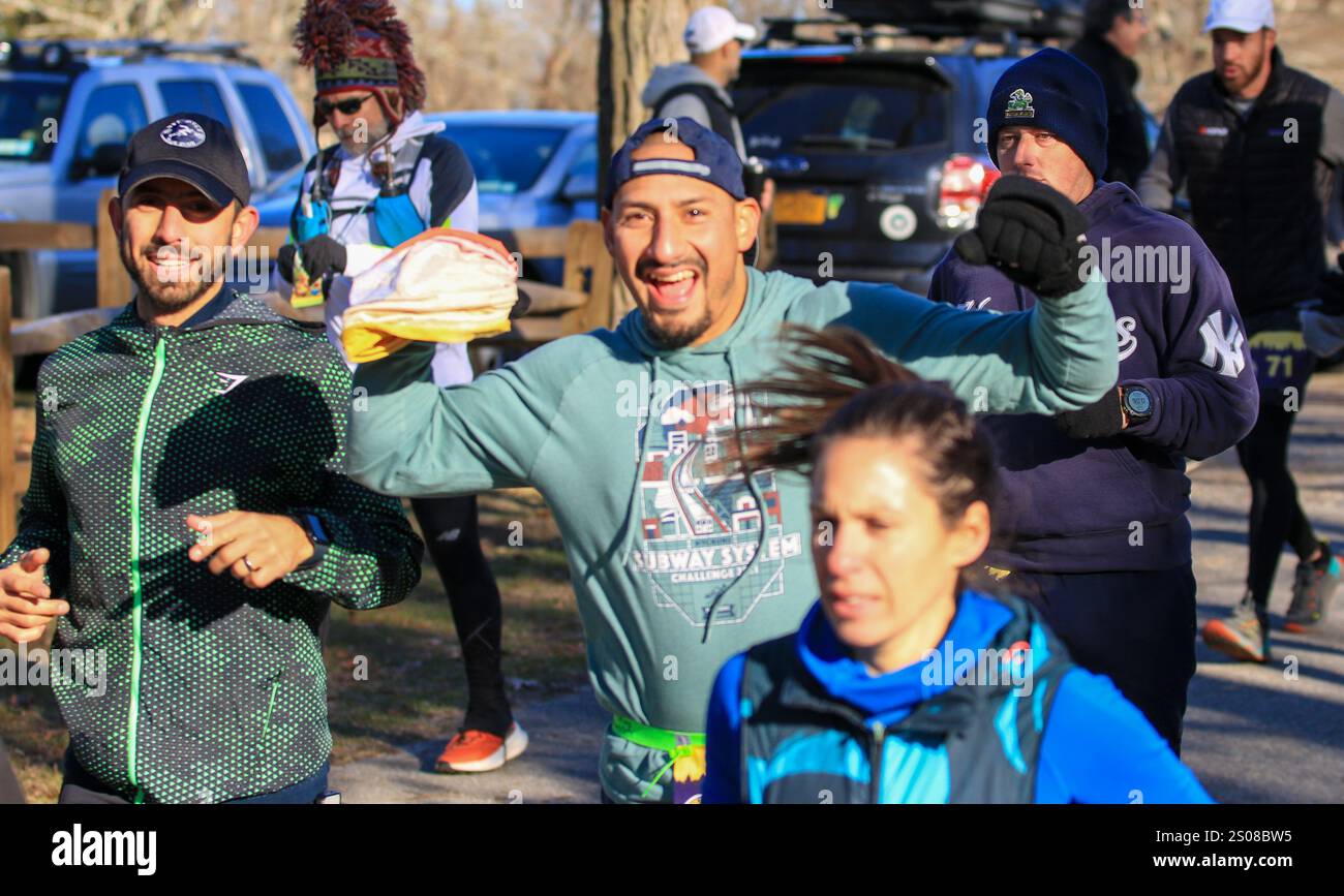 Smithtown, New York, États-Unis - 14 décembre 2024 : les participants sourient et acclament tout en courant le long d'un sentier entouré d'arbres lors d'une course. Banque D'Images