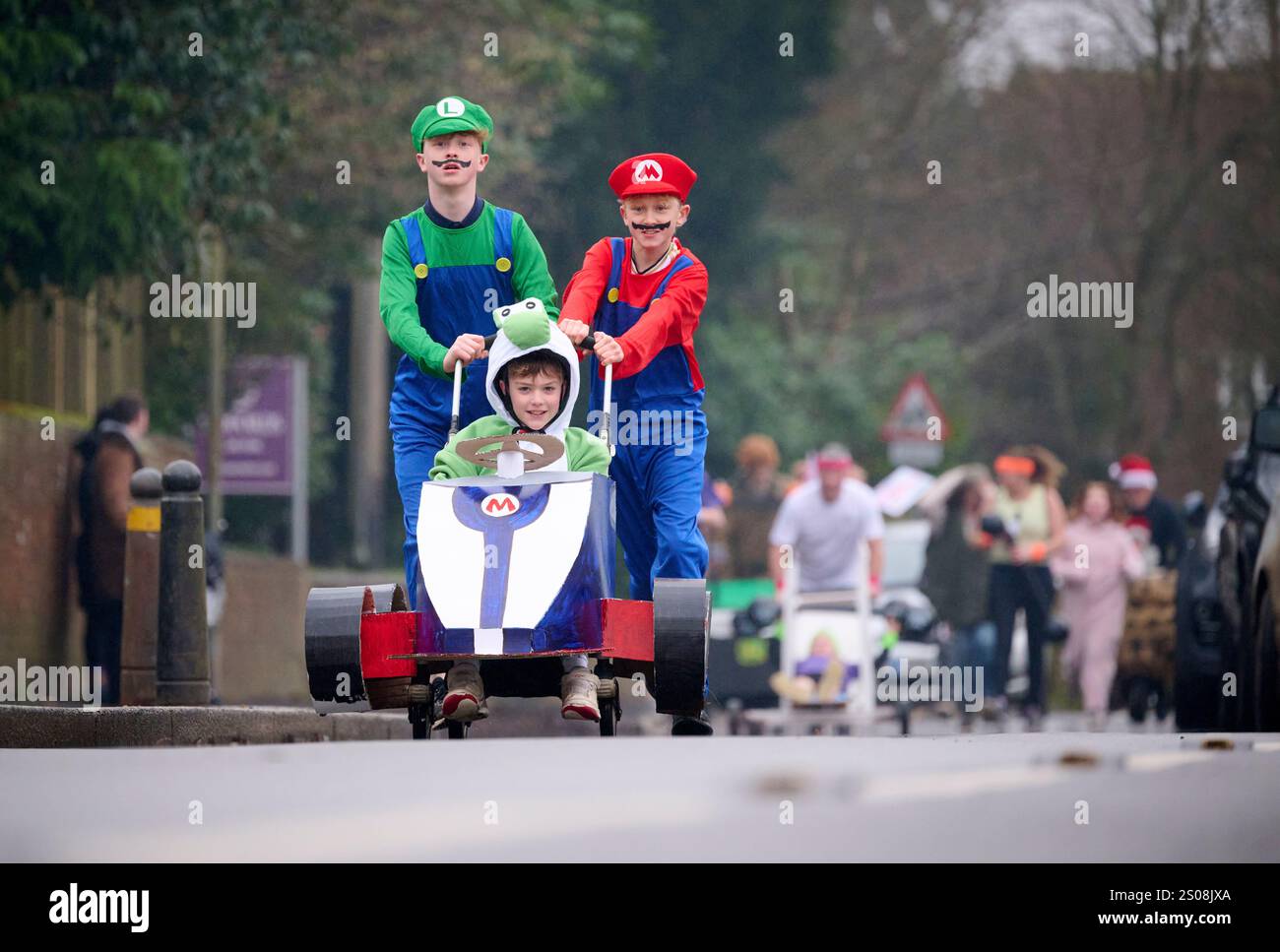 East Hoathly, Royaume-Uni. 26 décembre 2024. Course de landaus le lendemain de Noël : les équipes en tenue de course à travers le village d'East Hoathly dans l'est du Sussex collectant des fonds pour des œuvres caritatives locales. L'événement annuel commence et se termine au pub Kings Head au centre du village. Crédit : Jim Holden/Alamy Live News Banque D'Images