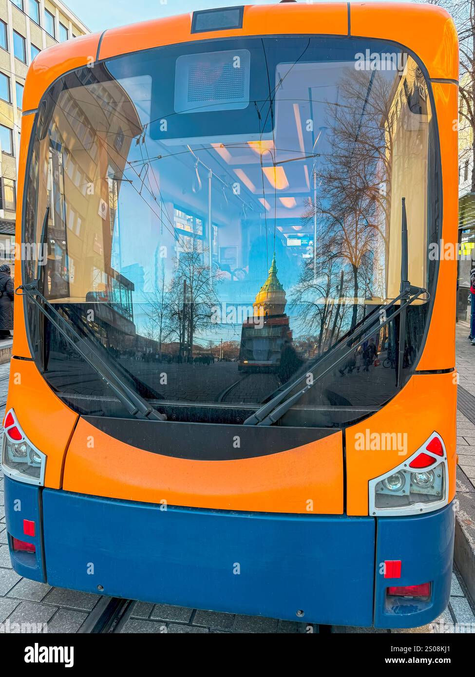 Tramway orange vif avec des reflets de la ville dans la fenêtre avant. Une scène urbaine moderne, les transports en commun Banque D'Images