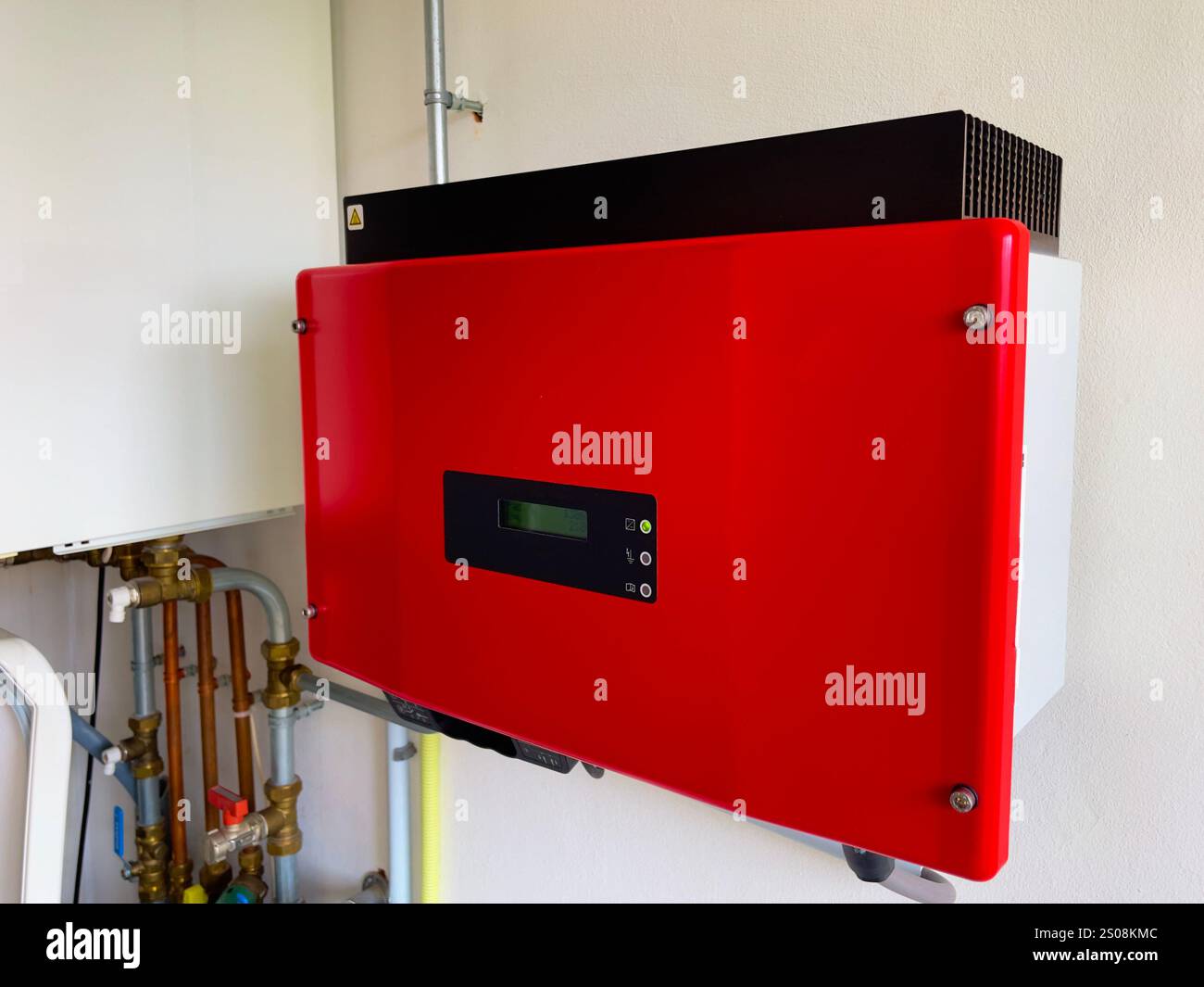 Gros plan d'un onduleur solaire rouge monté sur un mur blanc. Omvormer rouge. Générateur d'énergie solaire pour l'électricité 230V. Transition énergétique. Banque D'Images
