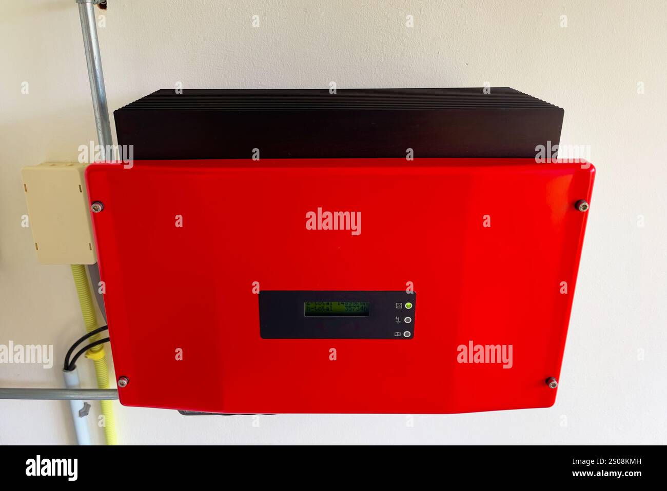 Gros plan d'un onduleur solaire rouge monté sur un mur blanc. Omvormer rouge. Générateur d'énergie solaire pour l'électricité 230V. Transition énergétique. Banque D'Images