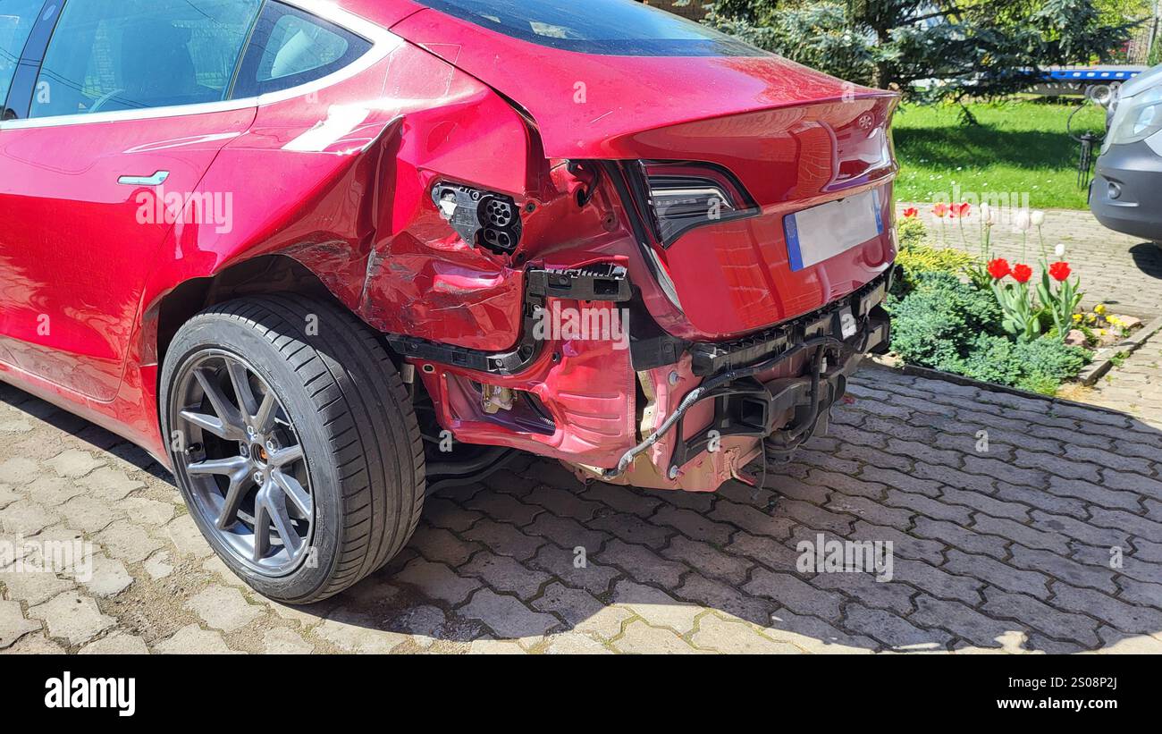 Vue rapprochée des dommages à la voiture rouge après un accident grave : pièces endommagées, métal froissé, éléments arrachés Banque D'Images