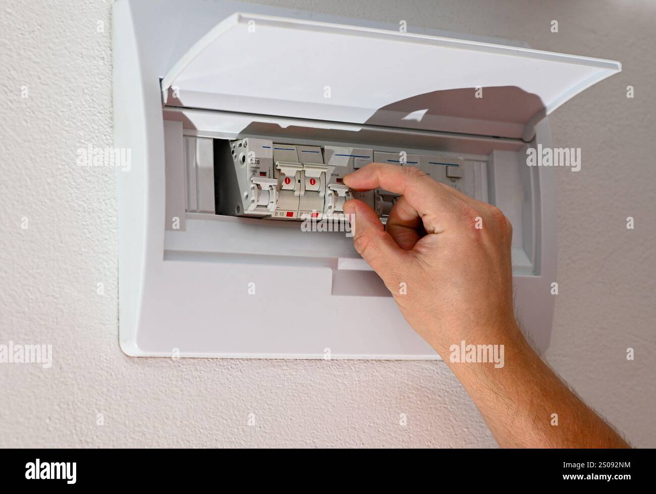 Gros plan d'un électricien actionnant un disjoncteur dans une boîte à fusibles, assurant la sécurité électrique et la distribution de l'alimentation. Banque D'Images