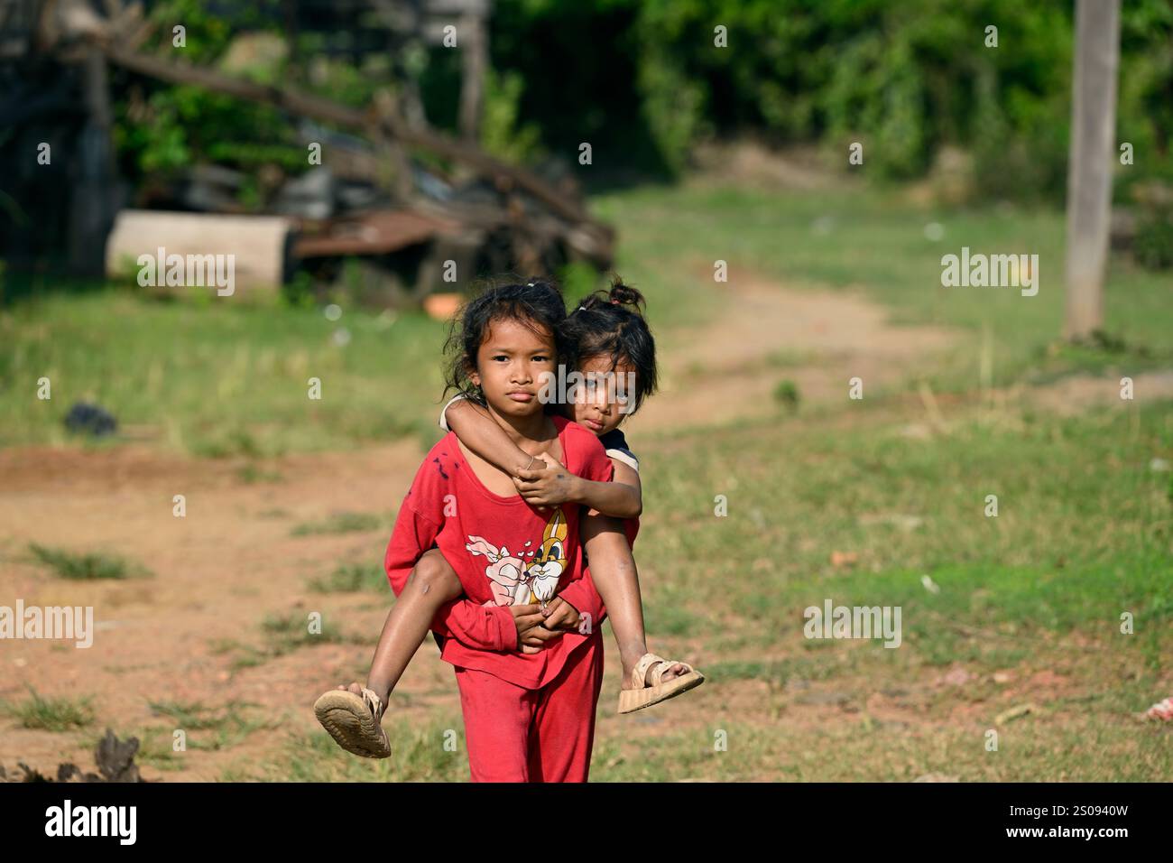 Une jeune fille cambodgienne portant sa sœur à Kratie, dans la campagne cambodgienne. Banque D'Images