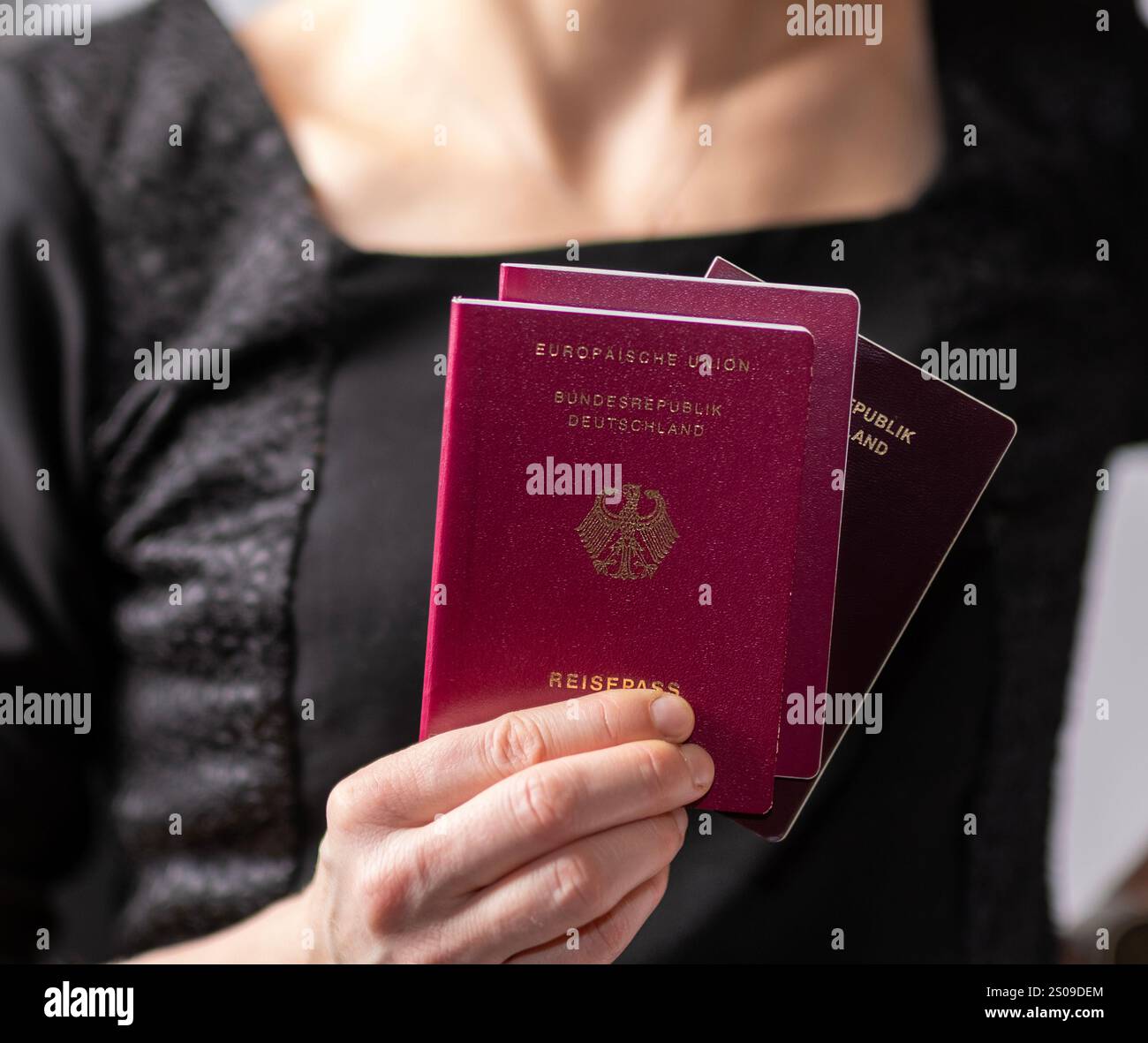 Gros plan d'une personne détenant trois passeports allemands. Une représentation symbolique du voyage, de l'identité et de la citoyenneté. Banque D'Images