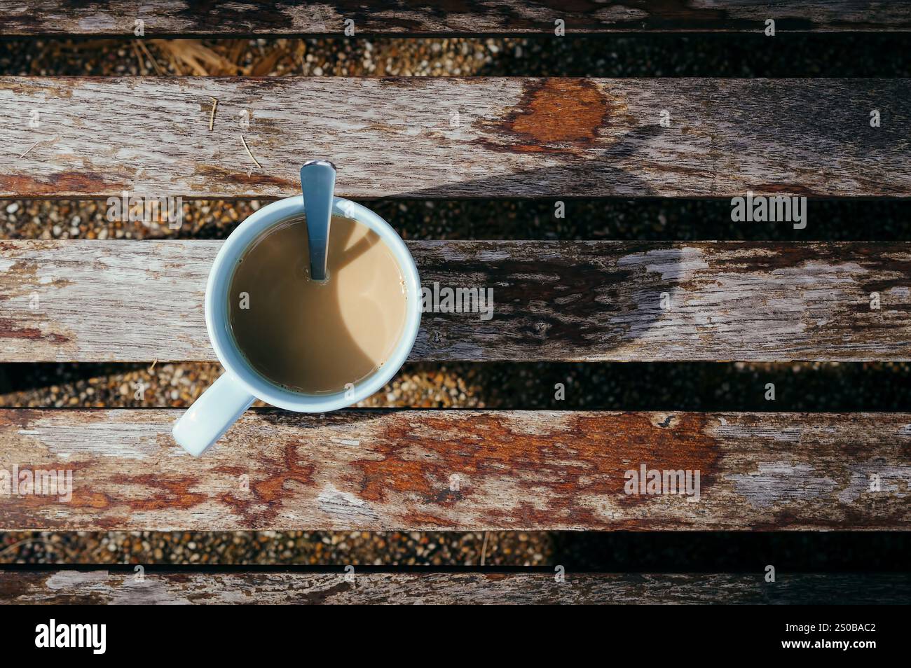 une tasse de café sur un banc en bois à l'ombre du lever du matin avec une cuillère à thé ressemblait à une horloge murale de 7 heures Banque D'Images