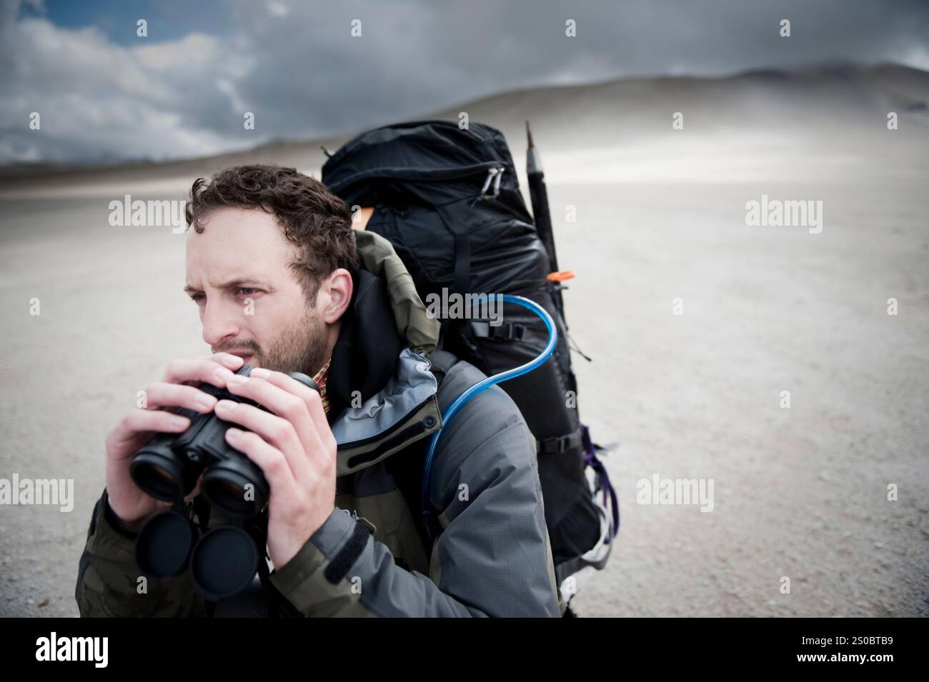 Un alpiniste scrute l'horizon pour trouver des ours bruns avec ses jumelles, Valley of Ten Thousand Smokes, katmai National Park, Alaska. Banque D'Images