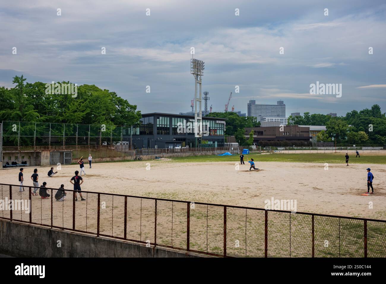 Osaka, Japon, 24 juin 2024 : un groupe d'hommes jouent un match de baseball sur un terrain de terre au cœur de la ville. Le baseball est le p le plus populaire du Japon Banque D'Images