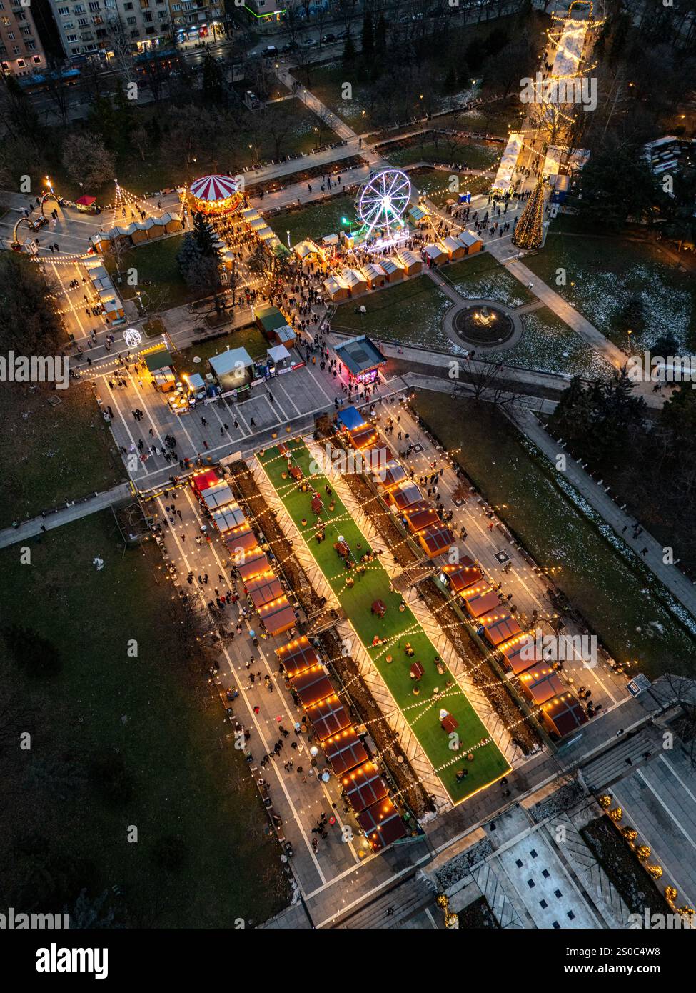 Une vue aérienne captivante du marché de Noël de Sofia au crépuscule, près de NDK, avec des lumières vibrantes, des stands festifs, une grande roue, et les fêtes de fin d'année. Banque D'Images