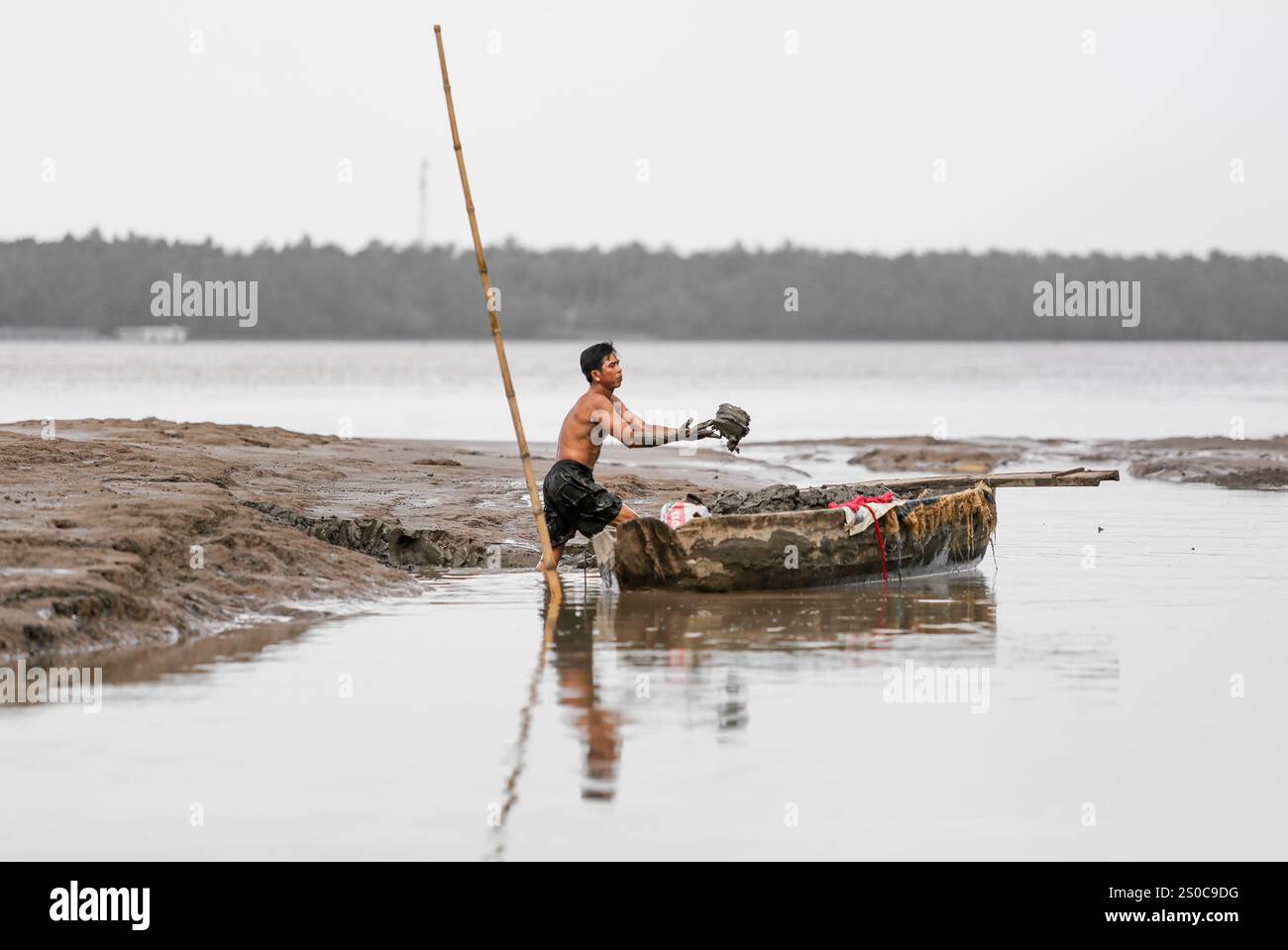 Delta du Mékong, Vietnam. 27 décembre 2024 : un vietnamien ramasse du sable et charge son bateau à la main. L’extraction de sable et de gravier (mines ou dragues) utilisée pour le béton dans l’industrie de la construction soulève des avertissements sur l’impact environnemental de la surexploitation des sédiments du lit fluvial (biodiversité et écosystème), mais aussi sur la vie des personnes vivant sur les berges. L’exploitation légale ou illégale du sable entraîne une érosion massive des berges, entraînant la perte de terres agricoles mais aussi l’effondrement des bâtiments et des maisons et le déplacement des populations. Crédit : KEVIN IZORCE/Alamy Live News Banque D'Images
