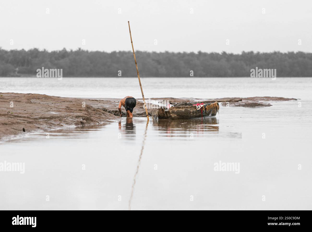 Delta du Mékong, Vietnam. 27 décembre 2024 : un vietnamien ramasse du sable et charge son bateau à la main. L’extraction de sable et de gravier (mines ou dragues) utilisée pour le béton dans l’industrie de la construction soulève des avertissements sur l’impact environnemental de la surexploitation des sédiments du lit fluvial (biodiversité et écosystème), mais aussi sur la vie des personnes vivant sur les berges. L’exploitation légale ou illégale du sable entraîne une érosion massive des berges, entraînant la perte de terres agricoles mais aussi l’effondrement des bâtiments et des maisons et le déplacement des populations. Crédit : KEVIN IZORCE/Alamy Live News Banque D'Images