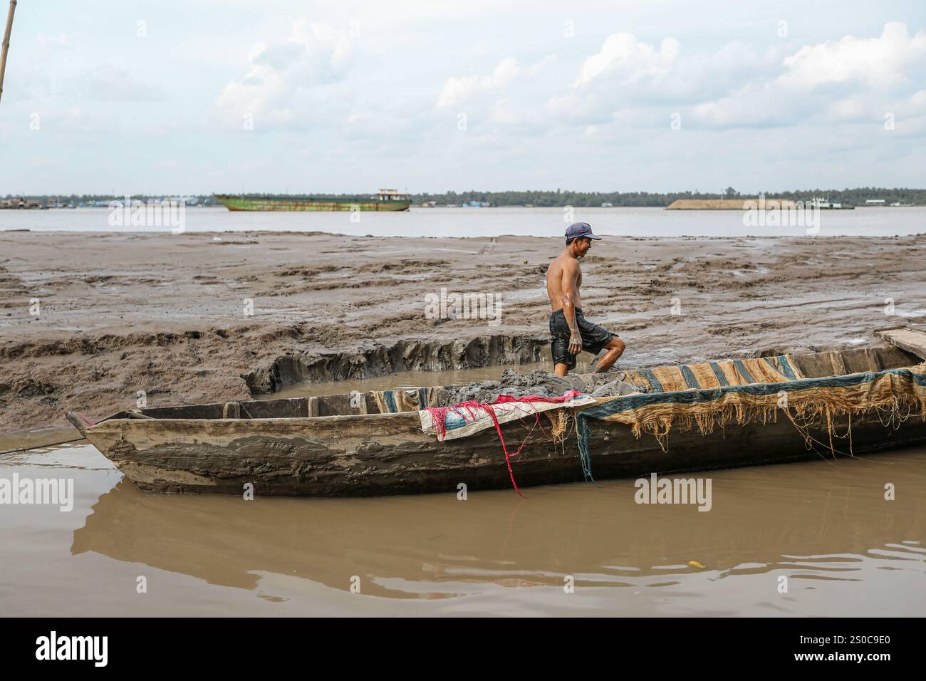 Delta du Mékong, Vietnam. 27 décembre 2024 : un vietnamien ramasse du sable et charge son bateau à la main. L’extraction de sable et de gravier (mines ou dragues) utilisée pour le béton dans l’industrie de la construction soulève des avertissements sur l’impact environnemental de la surexploitation des sédiments du lit fluvial (biodiversité et écosystème), mais aussi sur la vie des personnes vivant sur les berges. L’exploitation légale ou illégale du sable entraîne une érosion massive des berges, entraînant la perte de terres agricoles mais aussi l’effondrement des bâtiments et des maisons et le déplacement des populations. Crédit : KEVIN IZORCE/Alamy Live News Banque D'Images