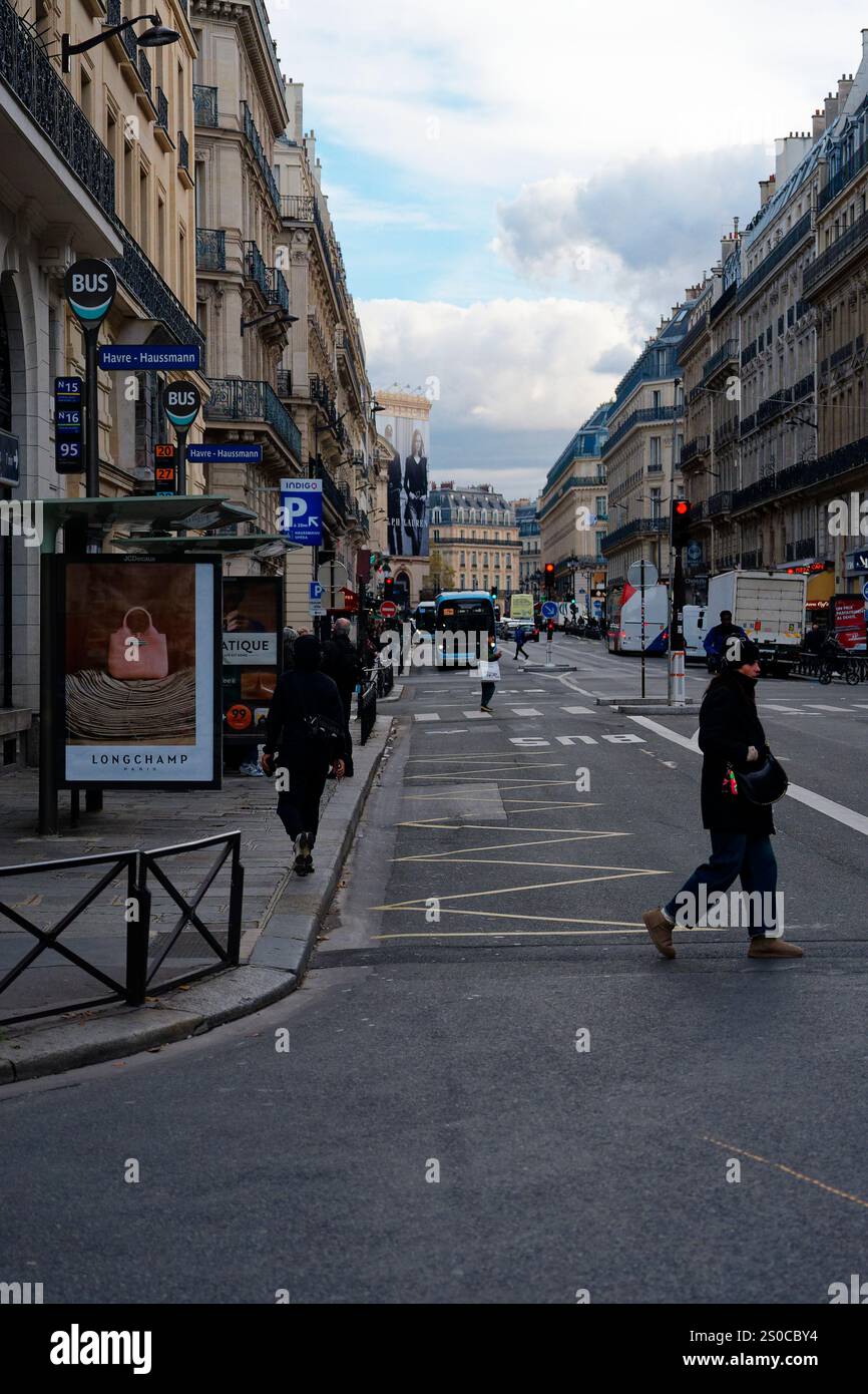 Rue animée de Paris avec piétons et véhicules à un carrefour par une journée nuageuse Banque D'Images