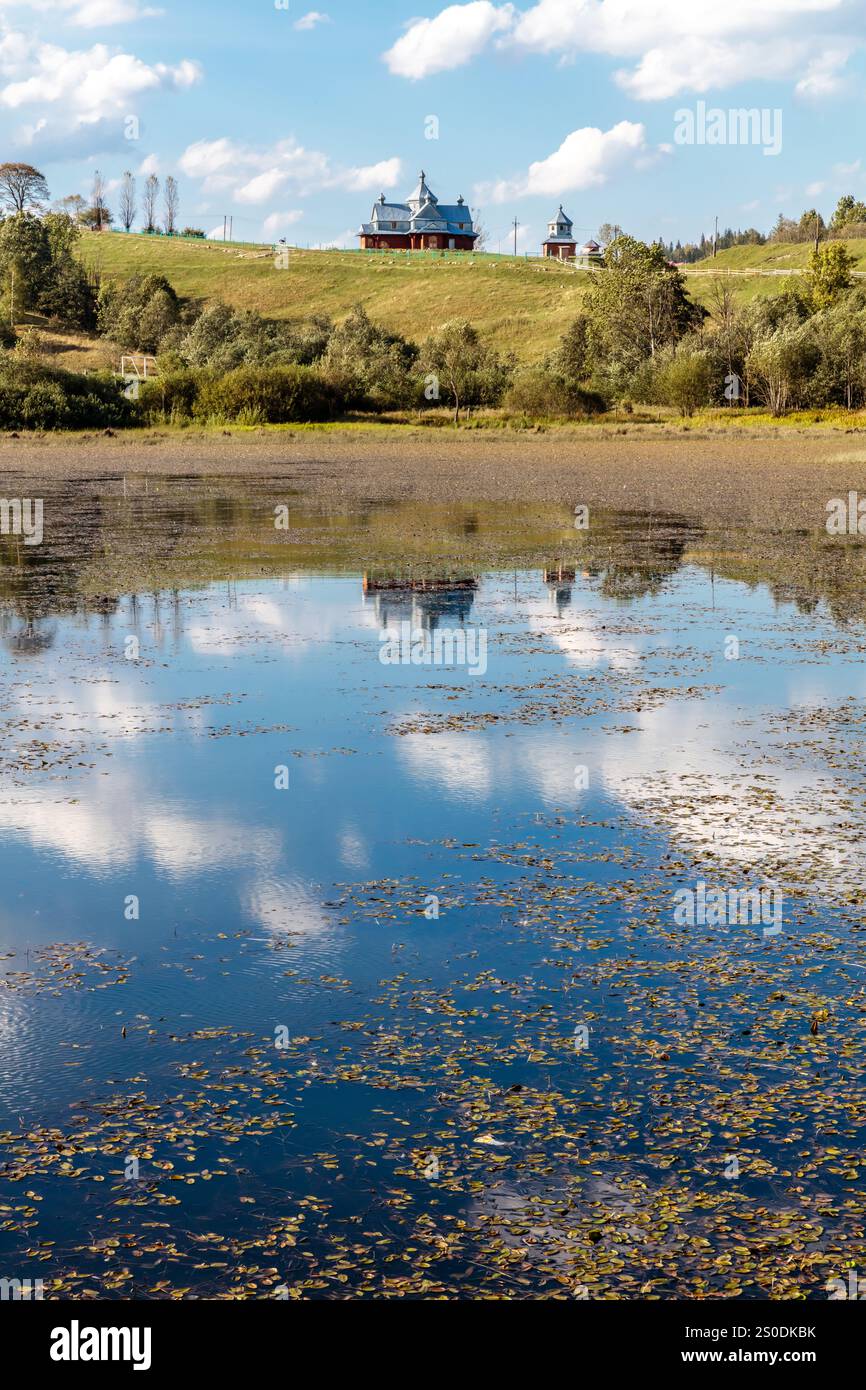 Un lac avec une maison en arrière-plan. L'eau est calme et le ciel bleu. La maison est entourée d'arbres et le lac est un reflet du hou Banque D'Images