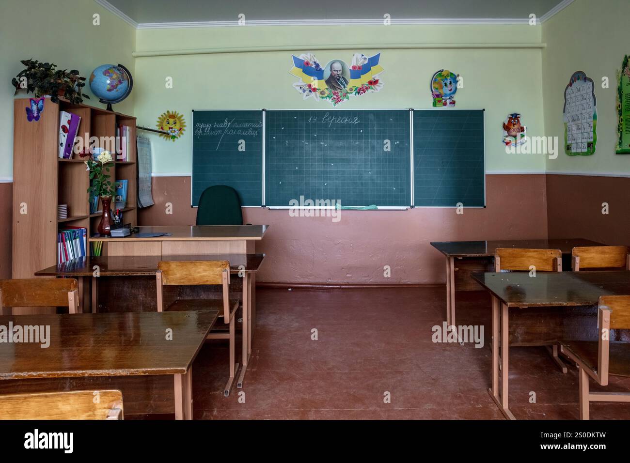 Une salle de classe avec un tableau vert et des bureaux en bois. La pièce est vide et les chaises sont disposées en rangées Banque D'Images