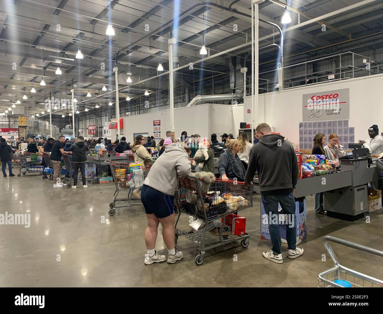 Costco Leeds magasin lieu de shopping personne pantalon rose shoppers dame acheter jusqu'à ce que les tills lumières lumineux clients Angleterre Yorkshire argent liquide vêtements nourriture - Image de stock capturée avec un smartphone
