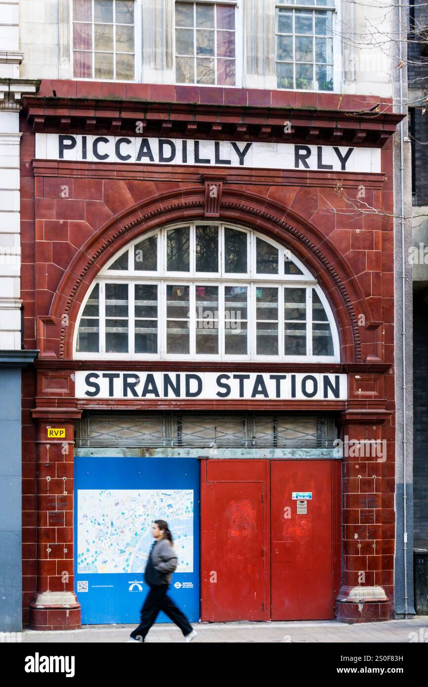 Une personne, le mouvement brouillé, passant devant la station de métro Aldwych fermée, anciennement Strand. Banque D'Images