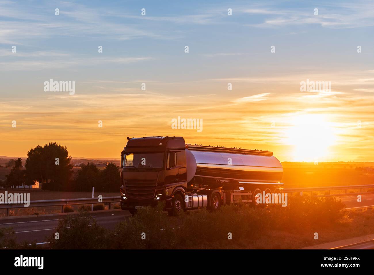 Un camion-citerne de nourriture conduisant sur une autoroute alors que le soleil se couche sur l'horizon, laissant place à la nuit, un travail exigeant sous des vues à couper le souffle. Banque D'Images