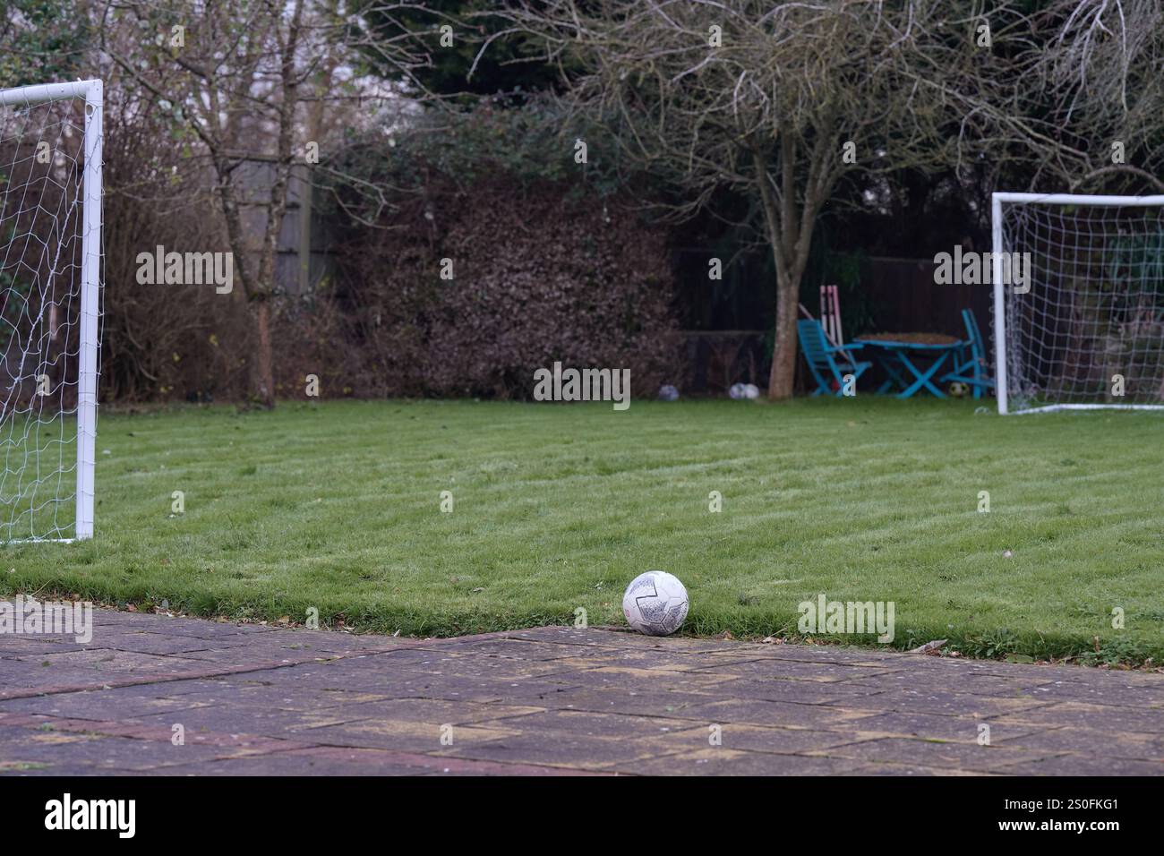 30 nov. 2024 - Angleterre Royaume-Uni : ballon de football unique dans un jardin vide à l'arrière avec de petits poteaux de but sur le bord Banque D'Images