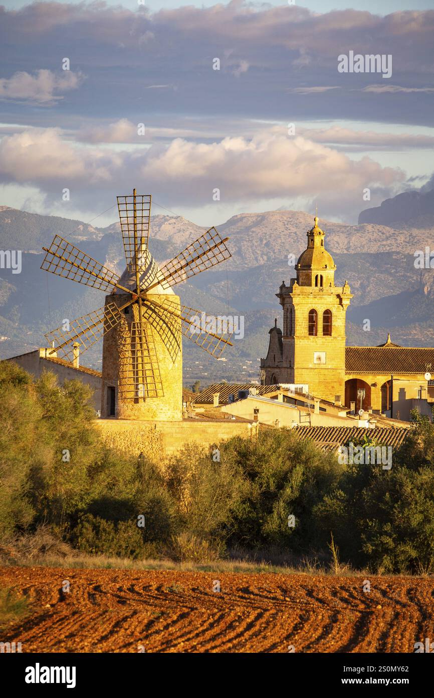 Moulin à vent et église dans un village avec montagnes et ciel nuageux, Algaida, Majorque, Espagne, Europe Banque D'Images