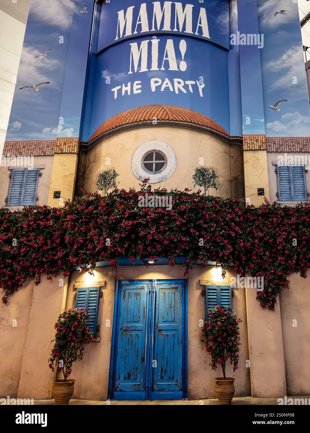Façade méditerranéenne vibrante promouvant Mamma Mia The Party, ornée de fleurs en fleurs et d'accents bleus de l'O2 Arena London UK Banque D'Images