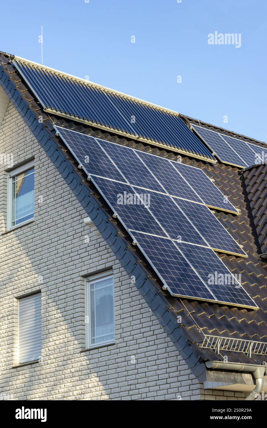 Toit d'une maison bifamiliale avec capteurs solaires et collecteurs à tubes à vide Banque D'Images