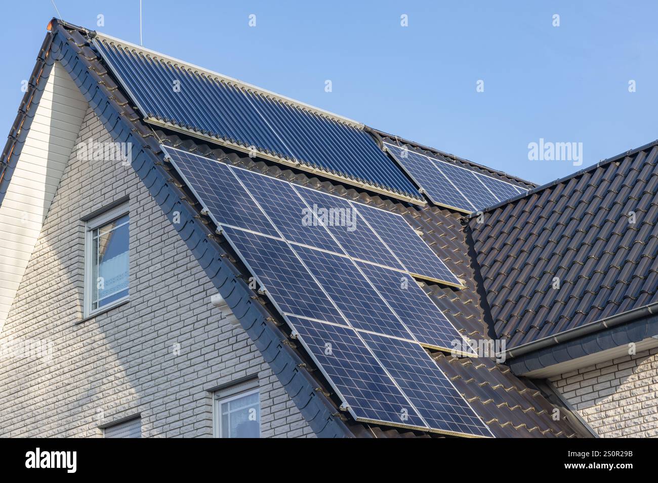 Toit d'une maison bifamiliale avec capteurs solaires et collecteurs à tubes à vide Banque D'Images