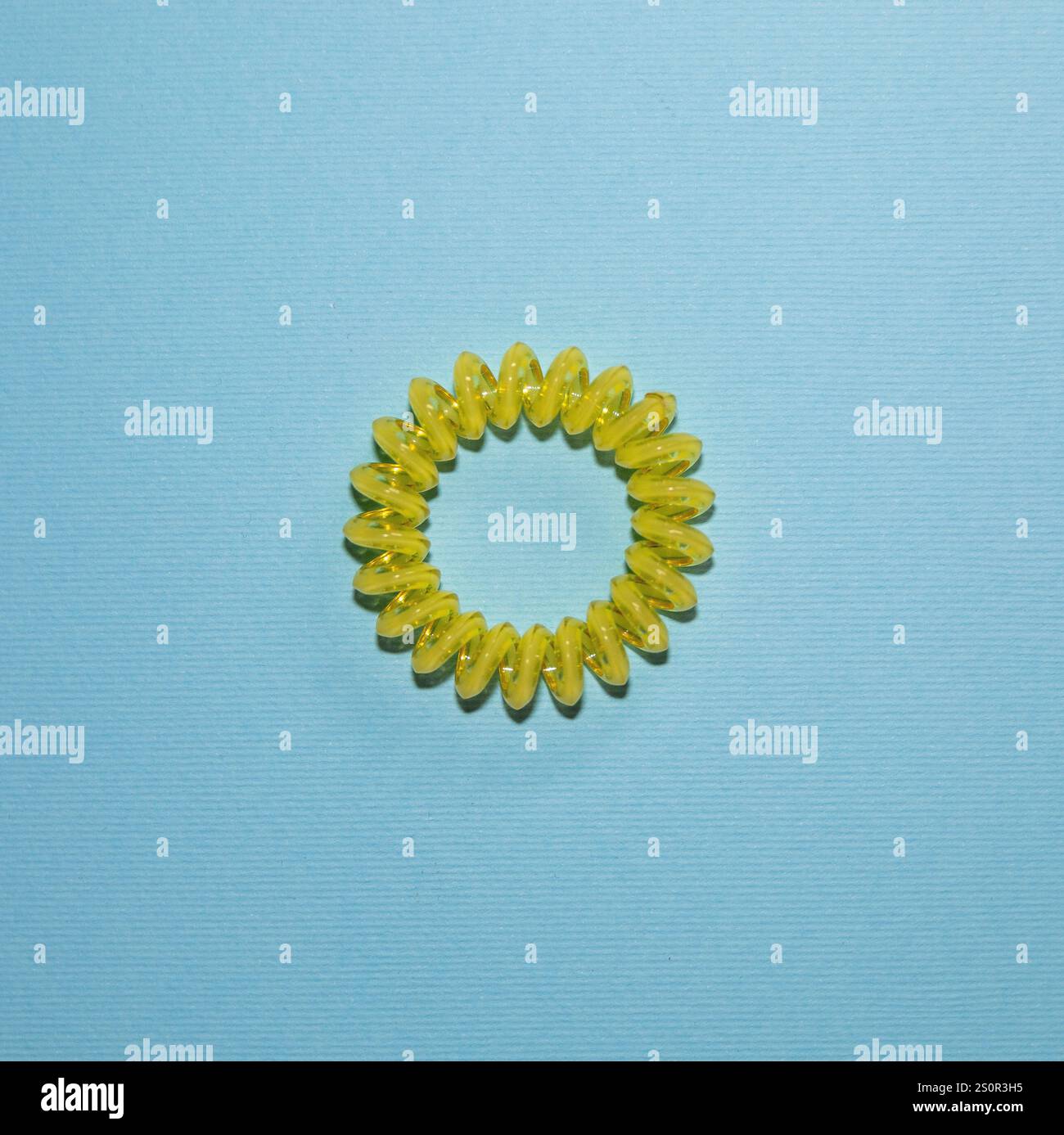 Cravate de cheveux en spirale jaune sur fond texturé bleu Banque D'Images
