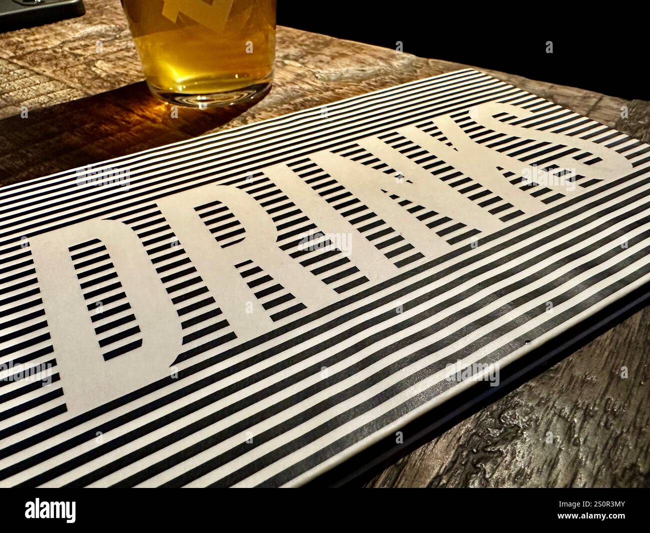 Un menu avec le mot boissons sur une table en bois dans le pub gastro et brasserie BRLO Brwhouse, verre de bière en arrière-plan, Berlin Schoeneberg, Allemagne Banque D'Images