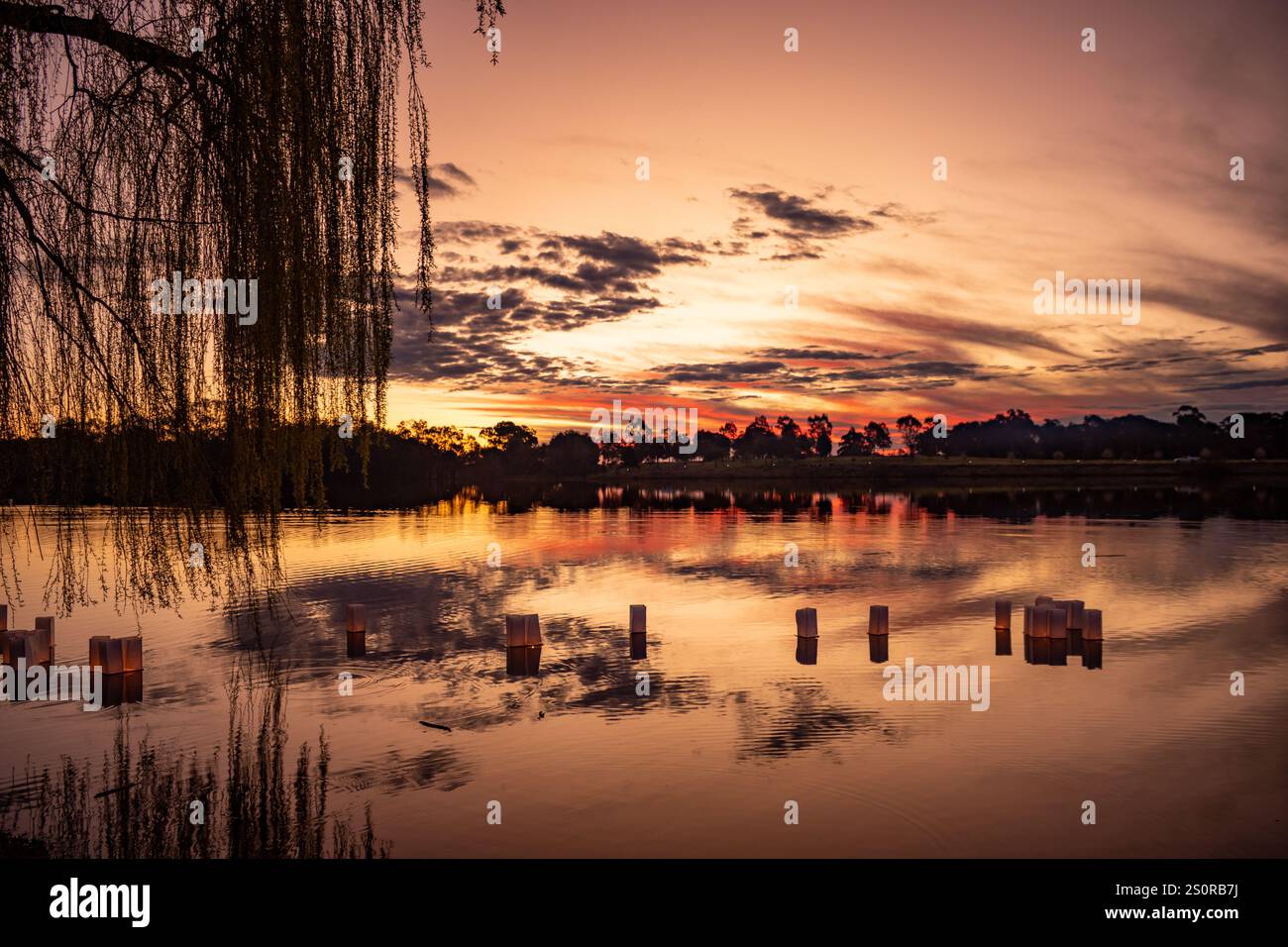 Lanternes de bougies chauffe-plat flottant sur un lac au coucher du soleil Banque D'Images
