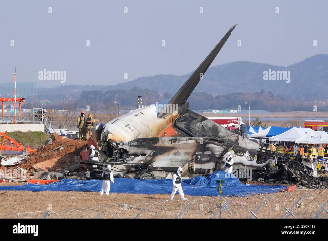 Firefighters and rescue team members work near the wreckage of a passenger plane at Muan International Airport in Muan, South Korea, Sunday, Dec. 29, 2024. (AP Photo/Ahn Young-joon) Banque D'Images