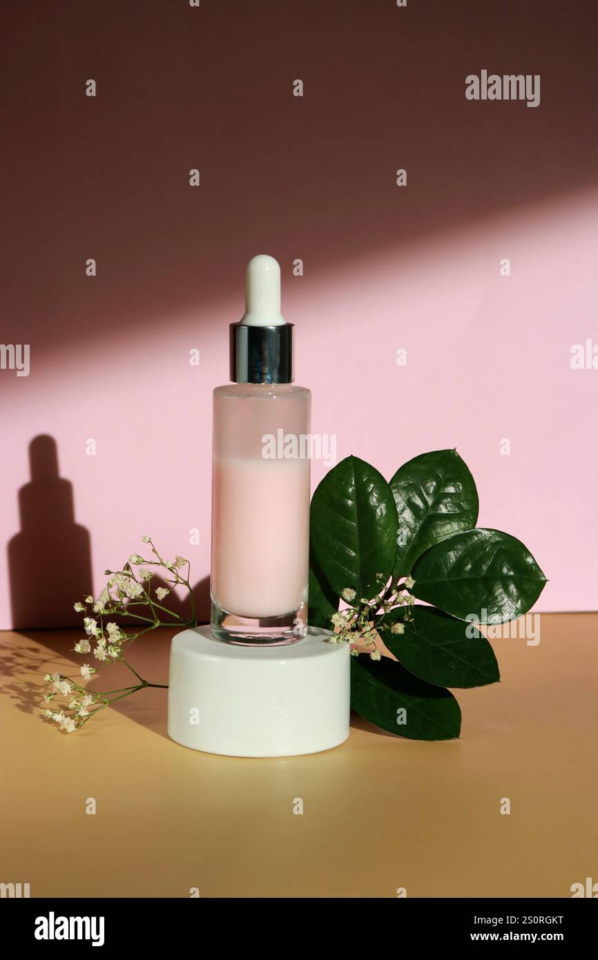 Une bouteille de lotion de sérum facial avec extrait de roses sur podium blanc et fond beige rose Banque D'Images