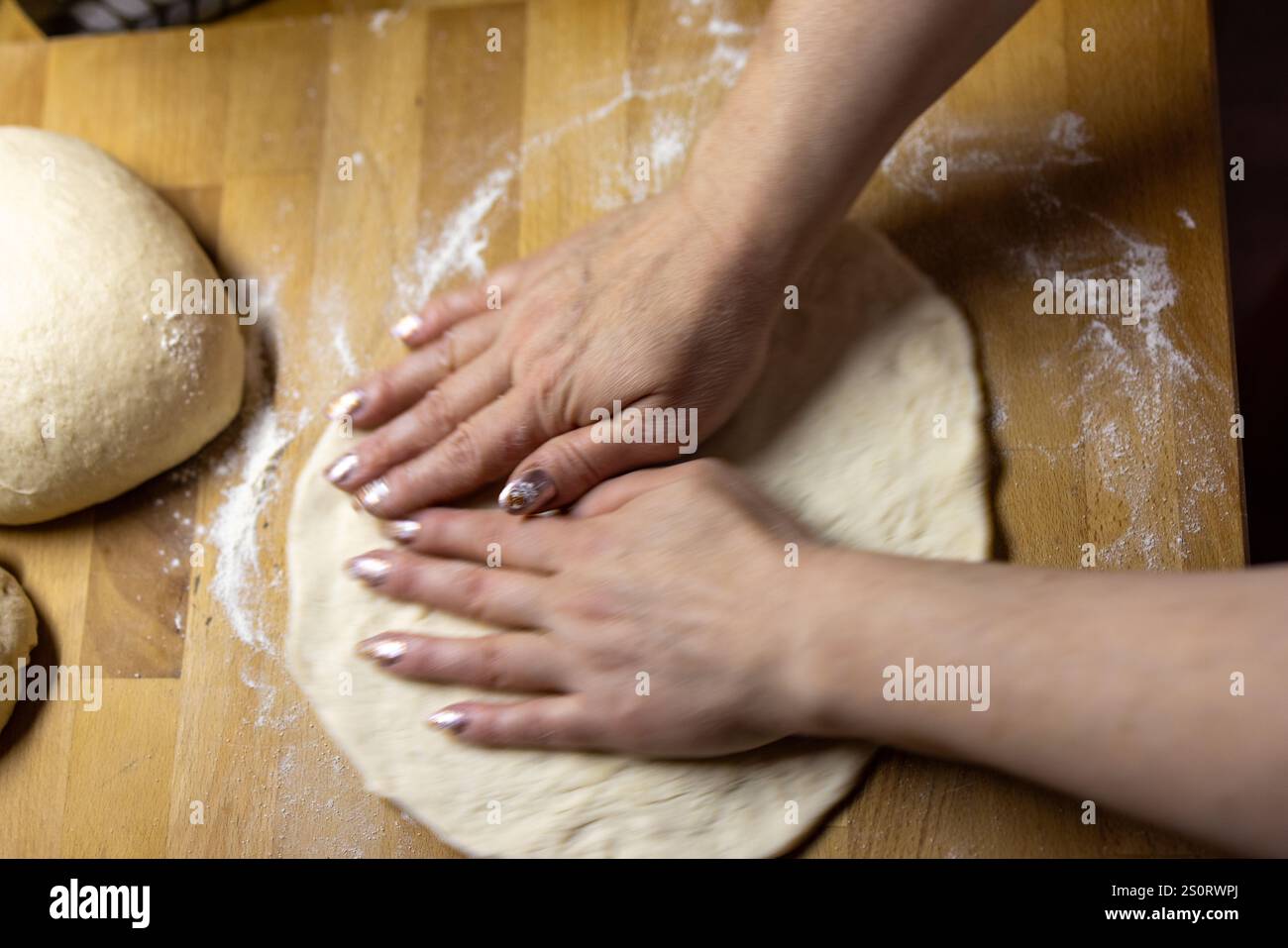 Mains rouler la pâte à pizza sur une surface en bois Banque D'Images
