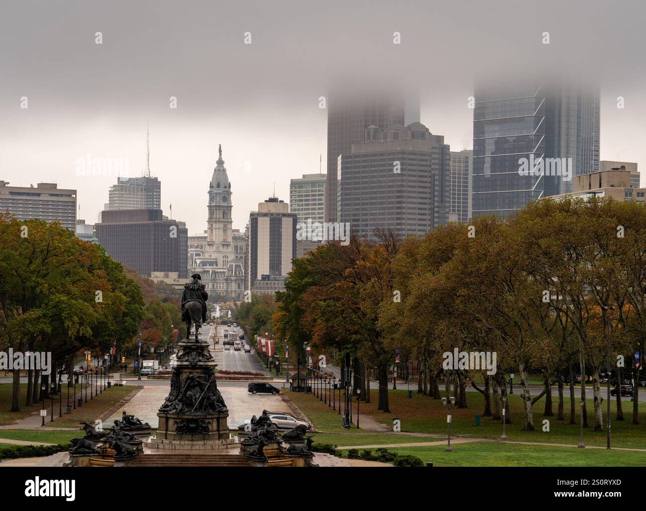 Une vue brumeuse sur les gratte-ciel de la ville avec de hauts bâtiments et une statue au premier plan. L'atmosphère est sombre avec un ciel couvert, mettant en valeur l'automne Banque D'Images