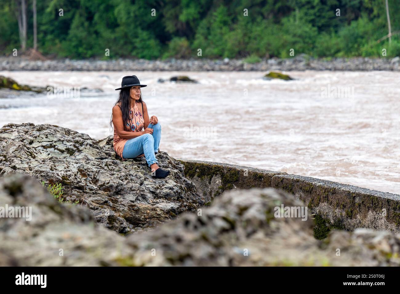 Première nation autochtone canadienne Wet'suwet'en femme observant comment les gens pêchent le saumon dans la rivière Bulkley, Witset, Colombie-Britannique, Canada. Banque D'Images