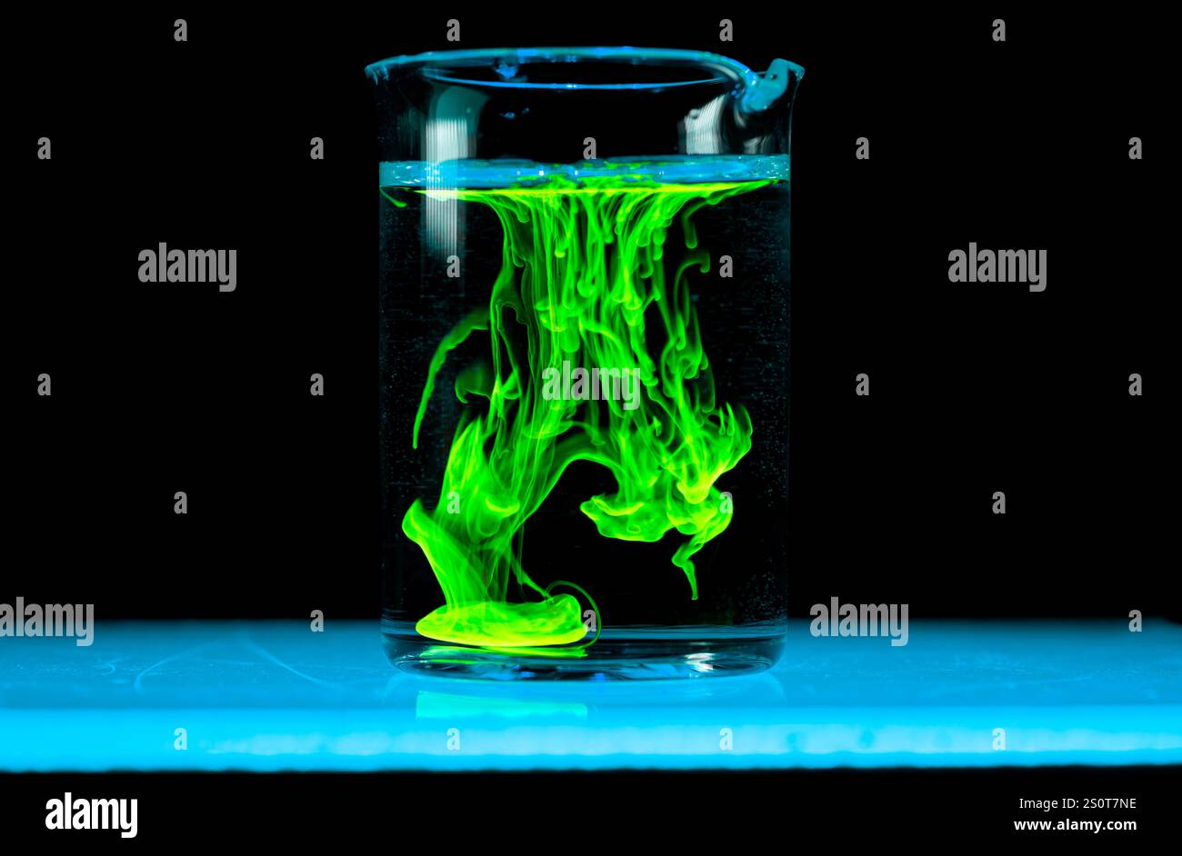 Dissolution et étalement d'une substance verte dans un flacon avec un liquide clair. Réaction chimique observée en laboratoire. Copyspace. Banque D'Images