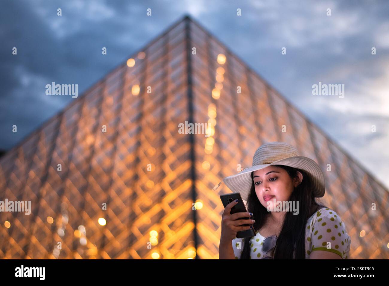Une belle femme devant le musée du Louvre, l'un des plus grands musées du monde et un monument historique. Un point de repère central de Paris, France. Banque D'Images