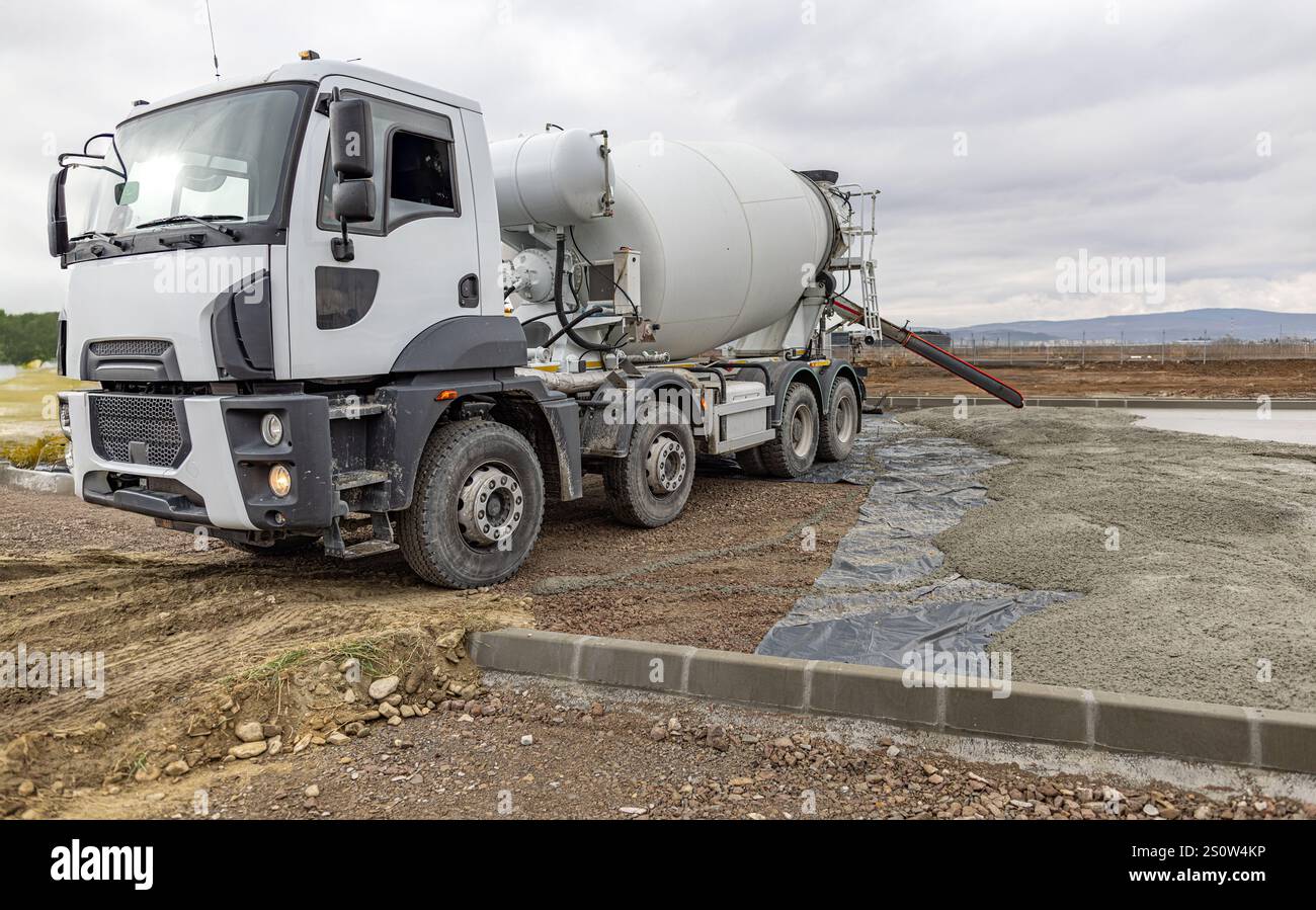 Camion malaxeur à béton coulant du ciment pendant les travaux de construction de routes Banque D'Images