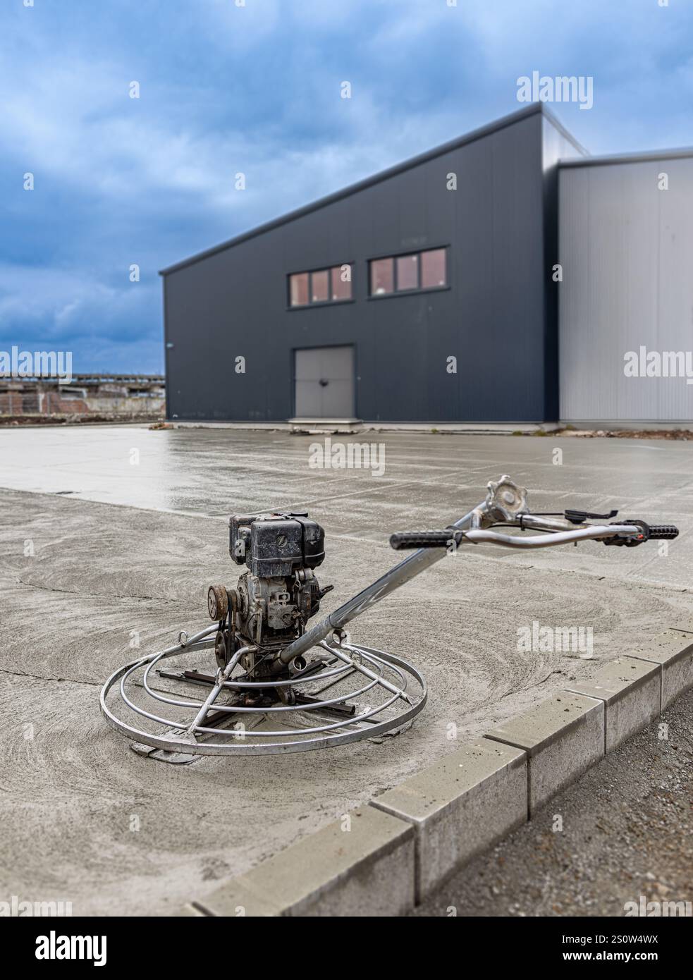 Procédé de finition de béton utilisant une truelle mécanique sur une dalle de béton fraîchement coulée sur un chantier de construction de bâtiments industriels Banque D'Images