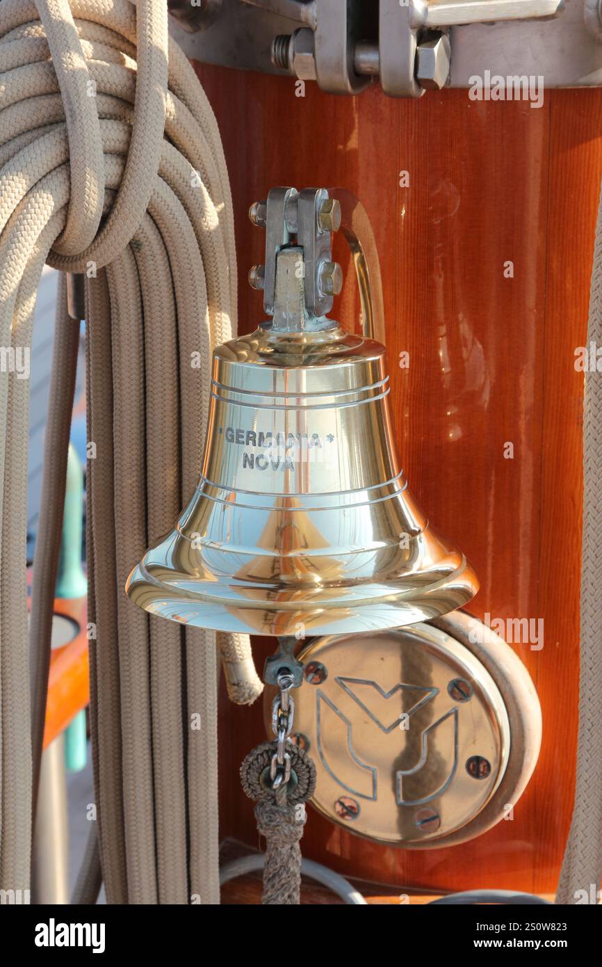 Cloche de navire en laiton poli montée sur un mât en bois avec des cordes nautiques Banque D'Images